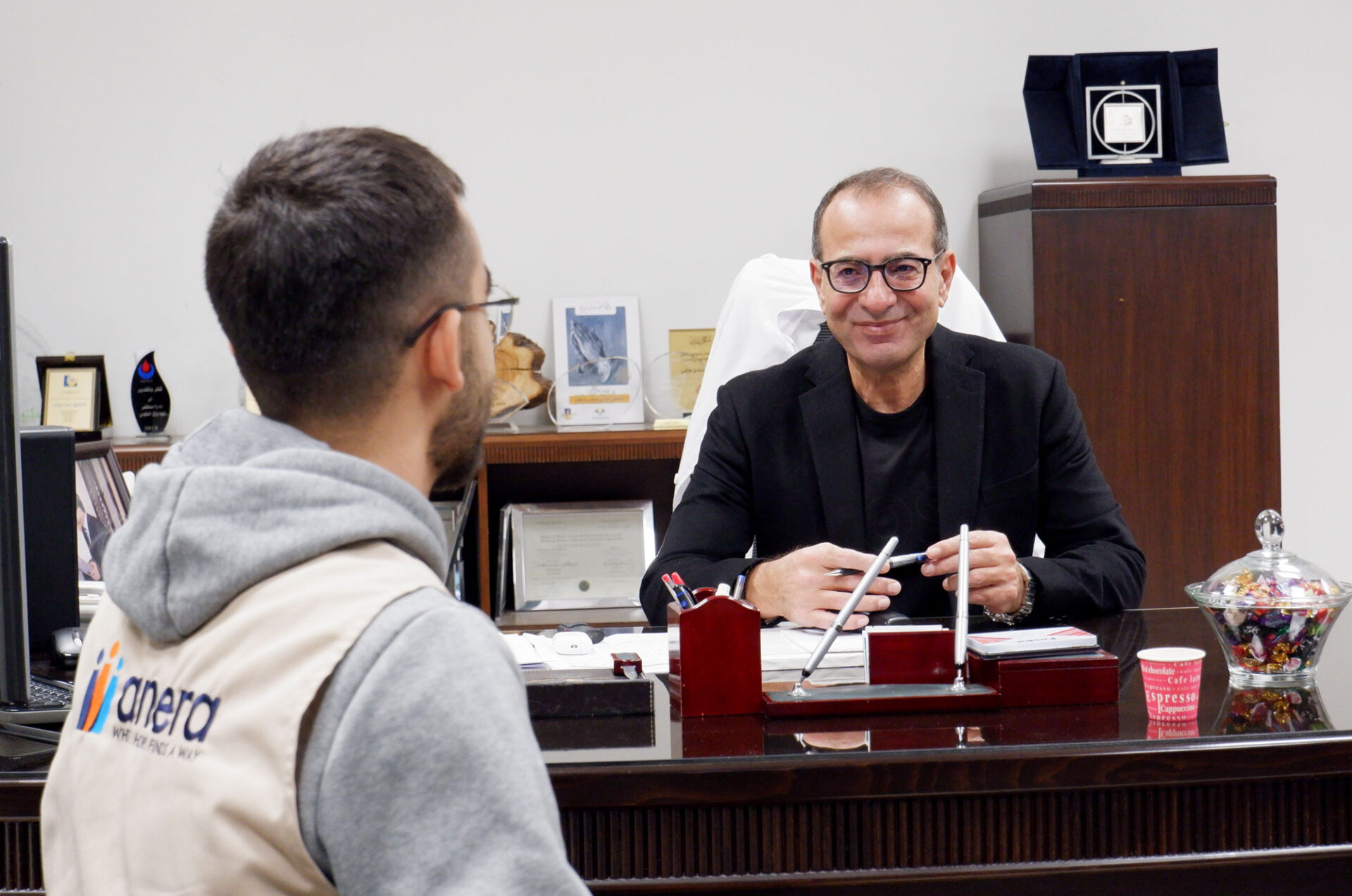 Dr. Hassan Wazni sits at his desk with Anera.