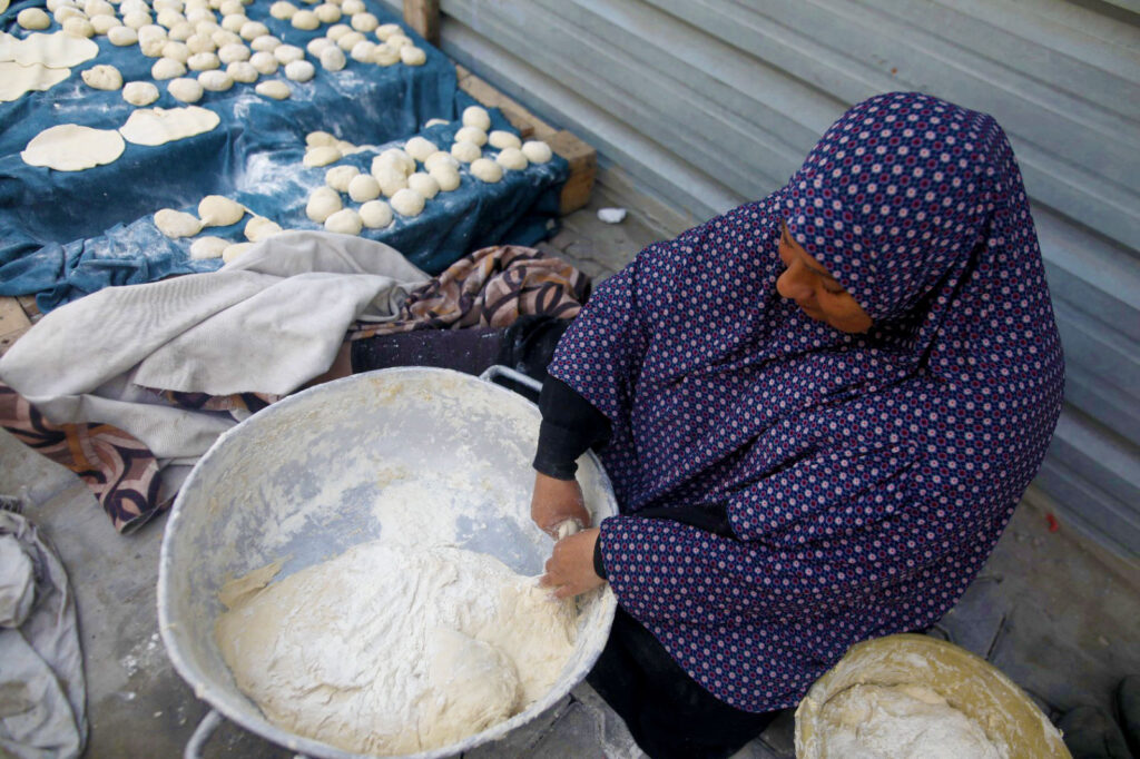 A woman makes bread outside in a big bowl.