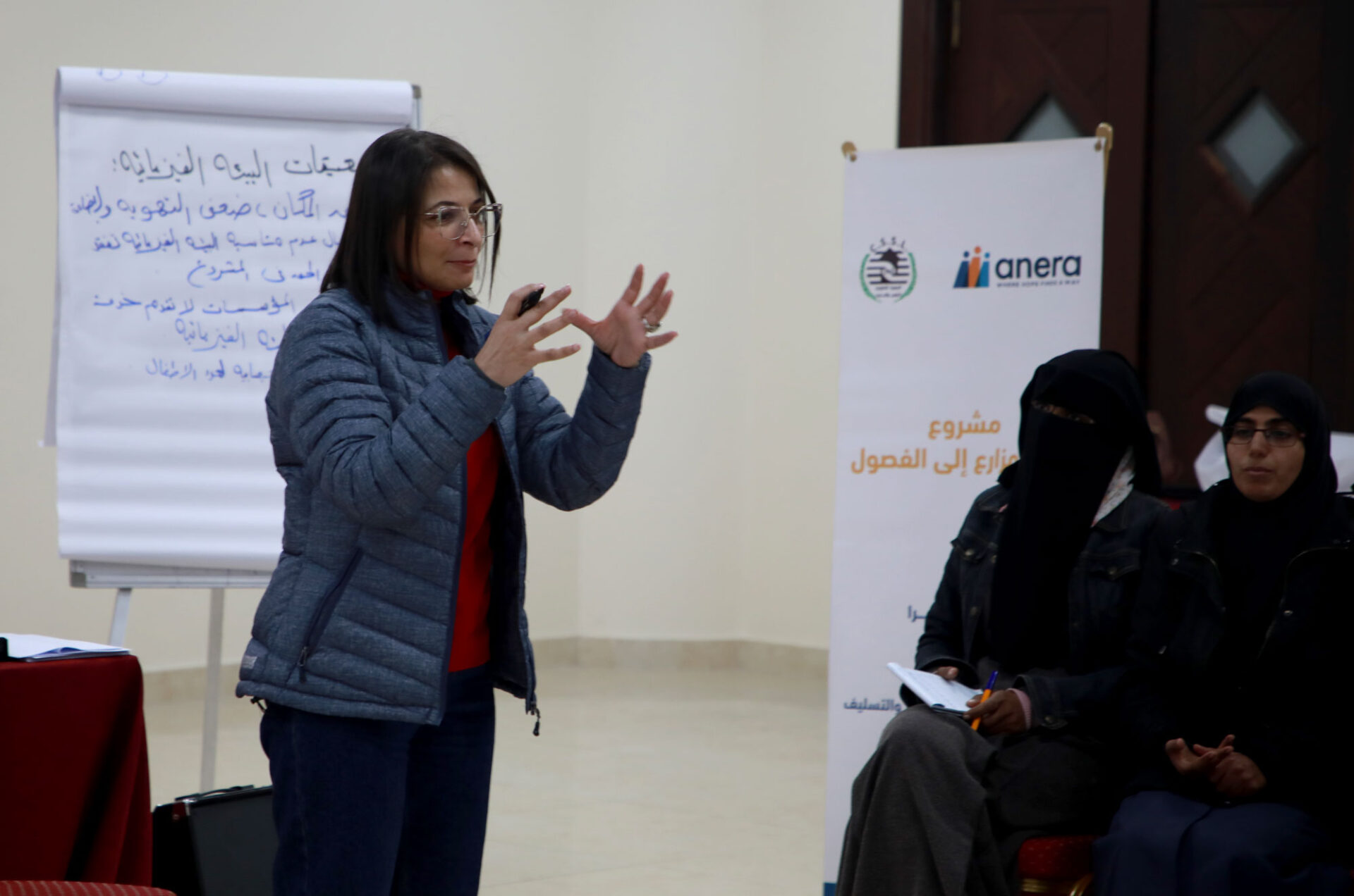 Laila presents to a group of women with a large standup easel with paper pad and notes behind her.