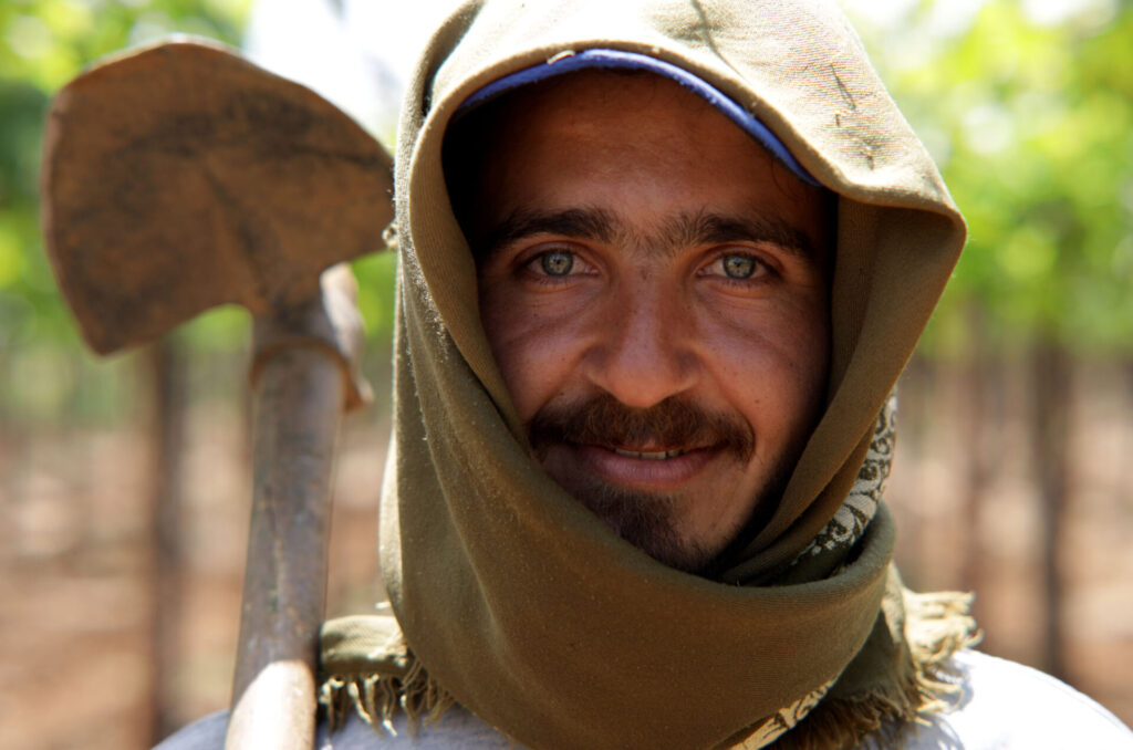 Ali hoists a hoe and smiles at the camera.