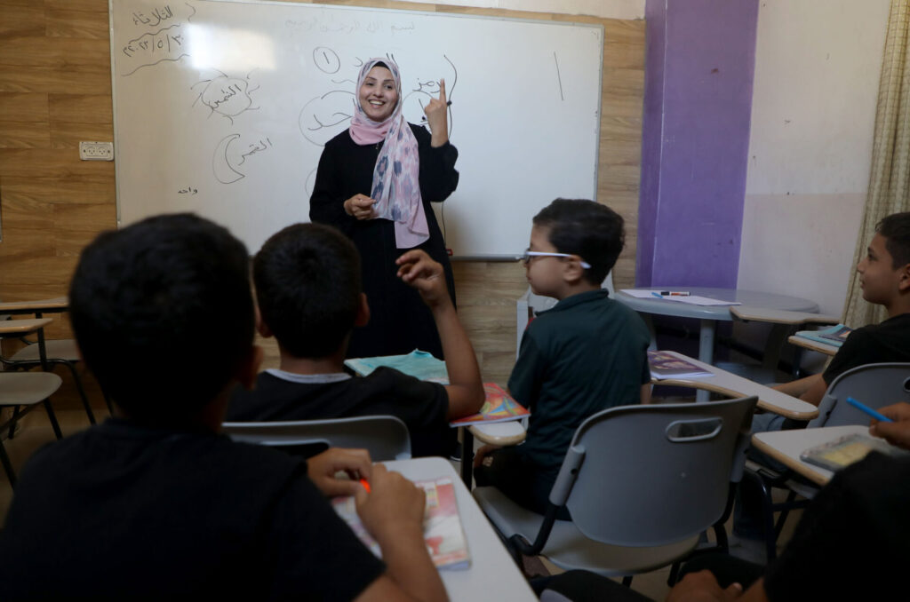 Nimeh stands in front of her classroom of children in Gaza.