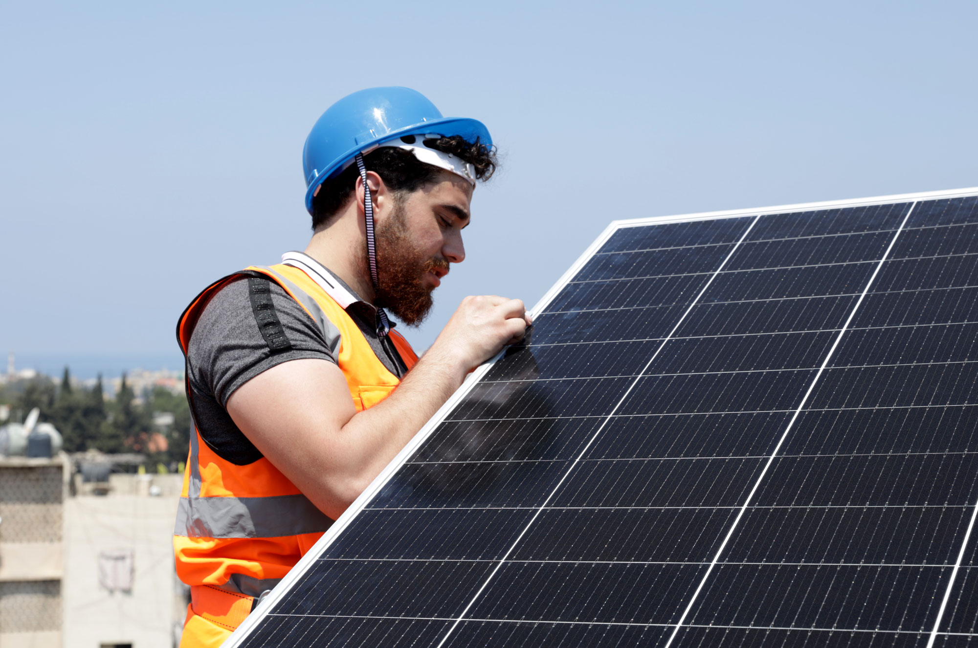 Vocational education student installs solar panel on rooftop.