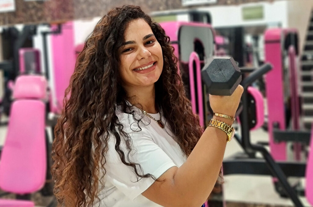 Mariam flexes with a dumbbell.