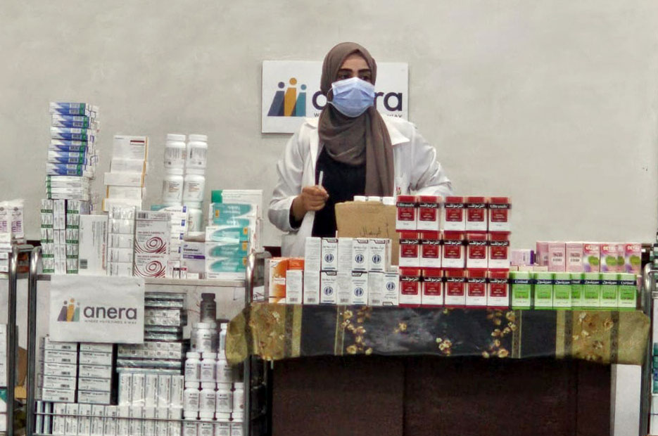 Healthcare provider at a table surrounded by packages of medicines.