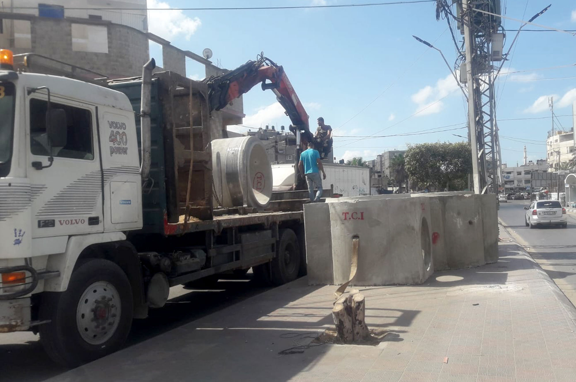 A truck unloads massive cement pipe segments that will direct water runoff.