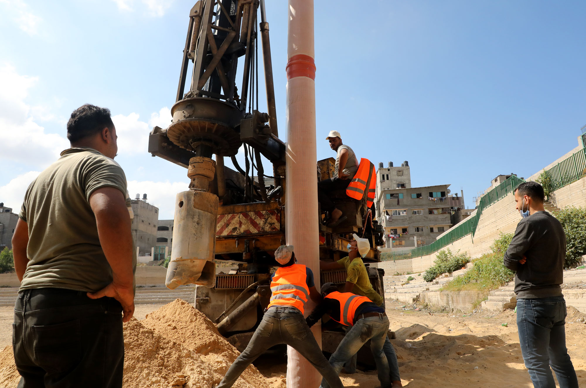 Workers handle a segment of pipe.