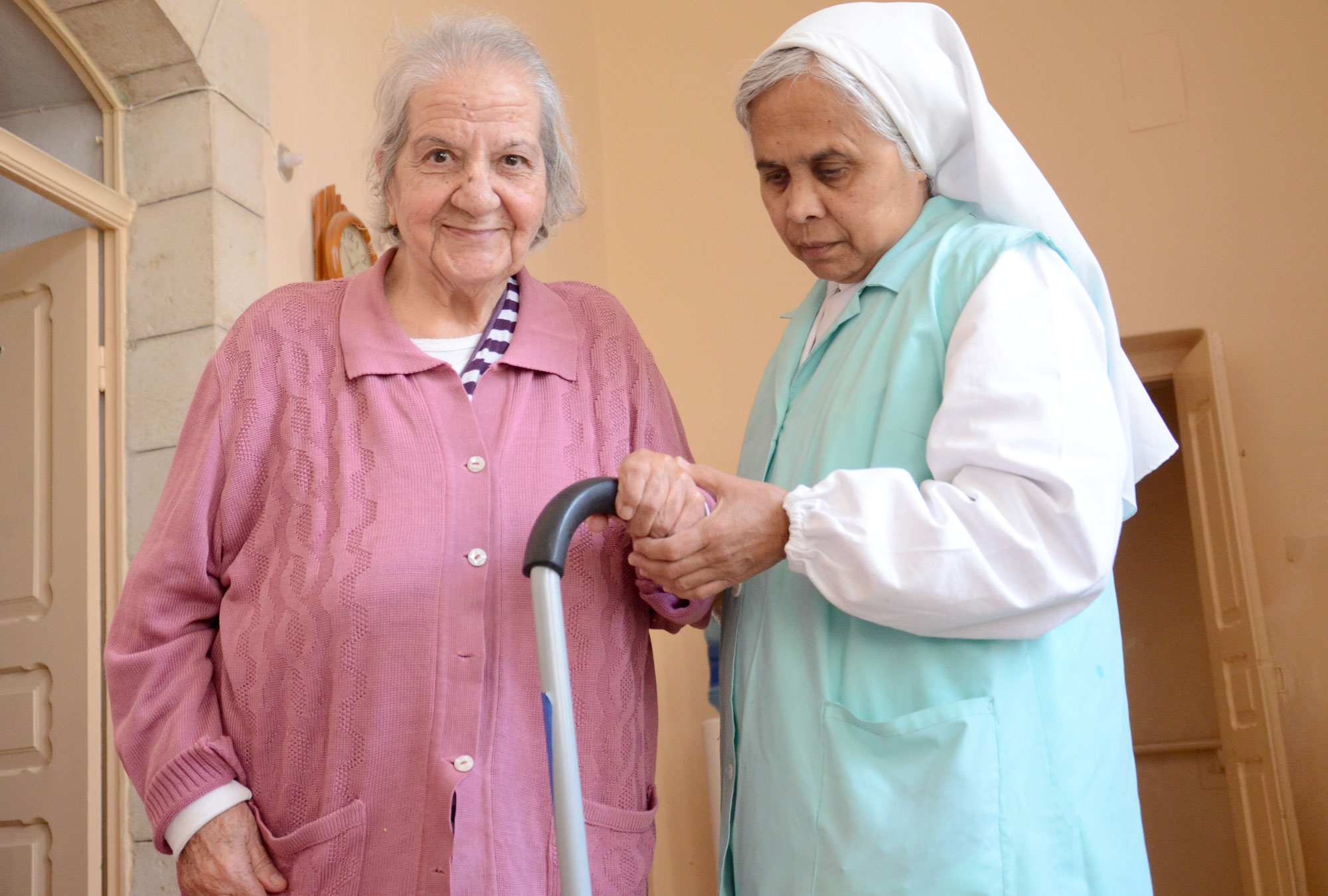 Julia, one of the residents at a Bethlehem home for the elderly, gets some help using her new cane from Anera.