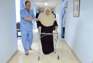 Maliha takes a walk down hospital hallway n Hebron with hew new walker from Anera.