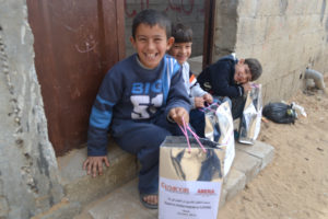 Gaza kids smile at their bags of winter clothes from Anera, replacing what they lost in the December floods.
