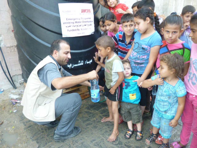 Anera Gaza staffer Sami helps children get water from a tank Anera set up in their Gaza community.