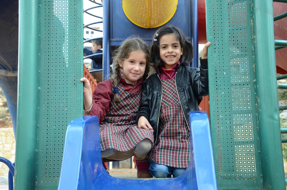 Palestinian girls enjoying the slides in the playground Anera built in their West Bank community of Al Bireh.