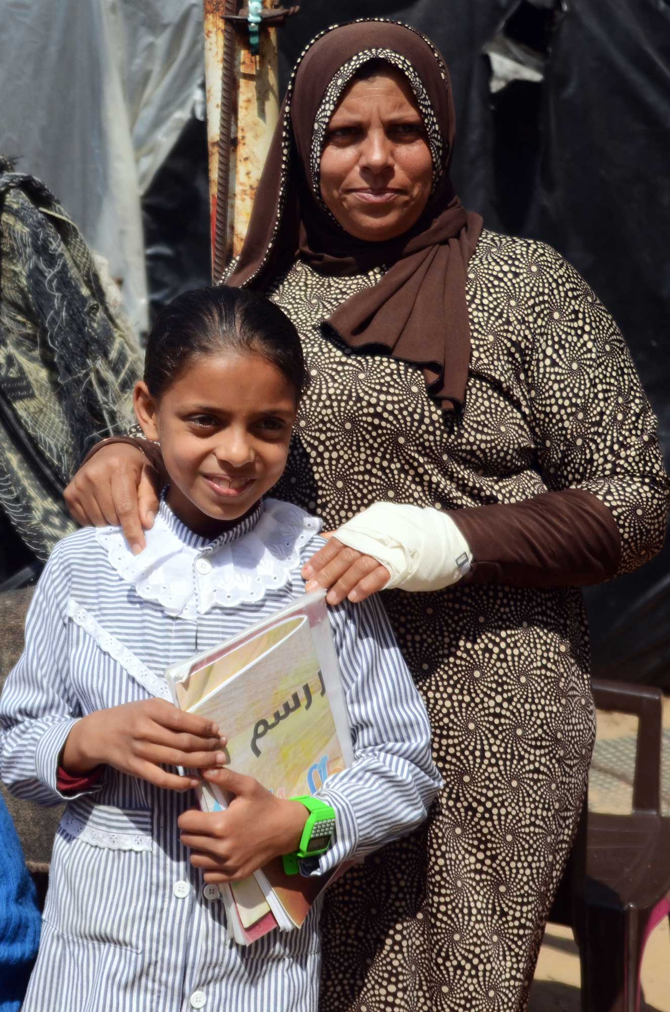 Laila and her daughter Maram stand in front of their home.