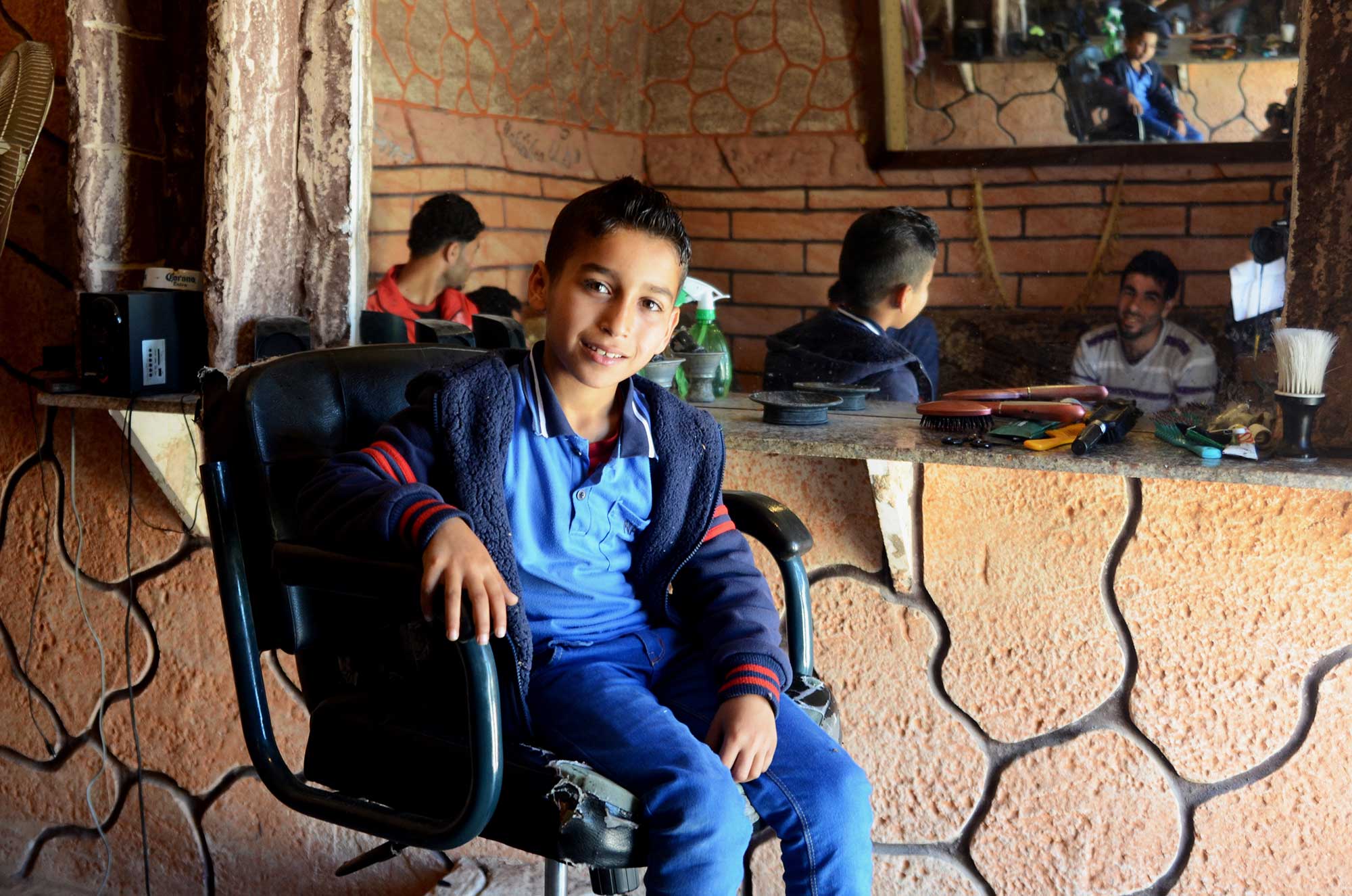 A young boy admires his new haircut at the barbershop.