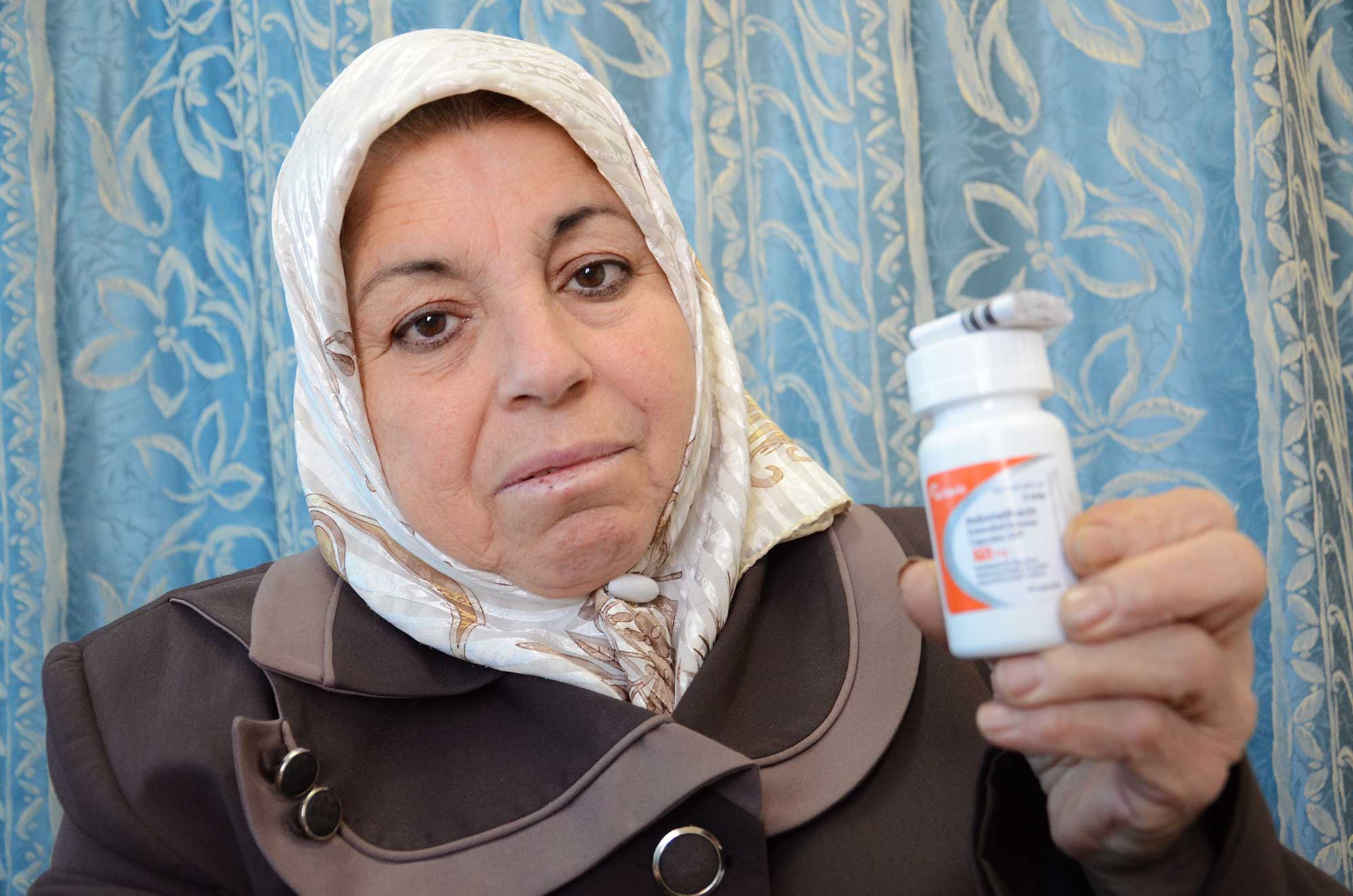 Mufida holds up a bottle of her new medicine, delivered by Anera to the Hebron clinic.