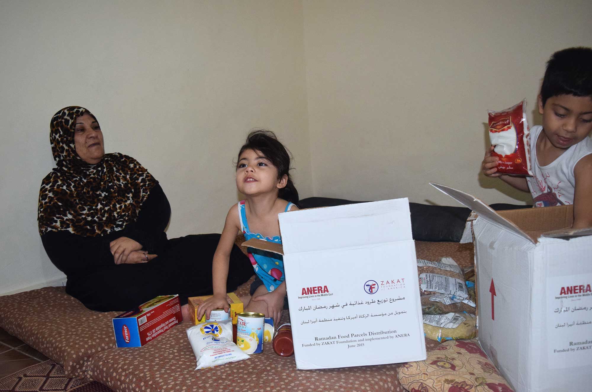 Four-year-old Nour El-Sham unpacks the food package she and her family has just received, thanks to funding from the Zakat Foundation.