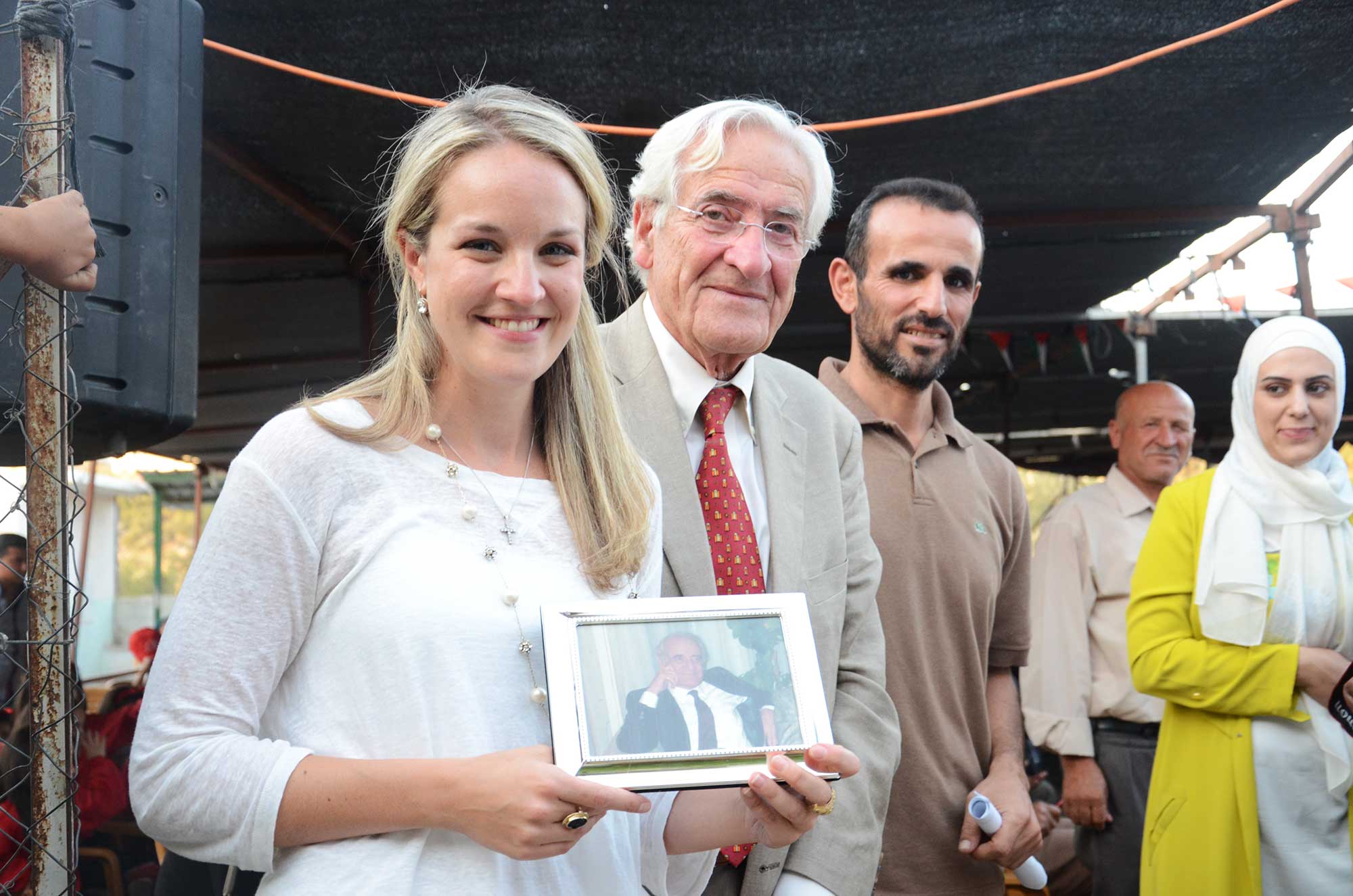Charles and his daughter Fiona hold up a photo of Bahjat Tarazi, for whom the preschool is named.