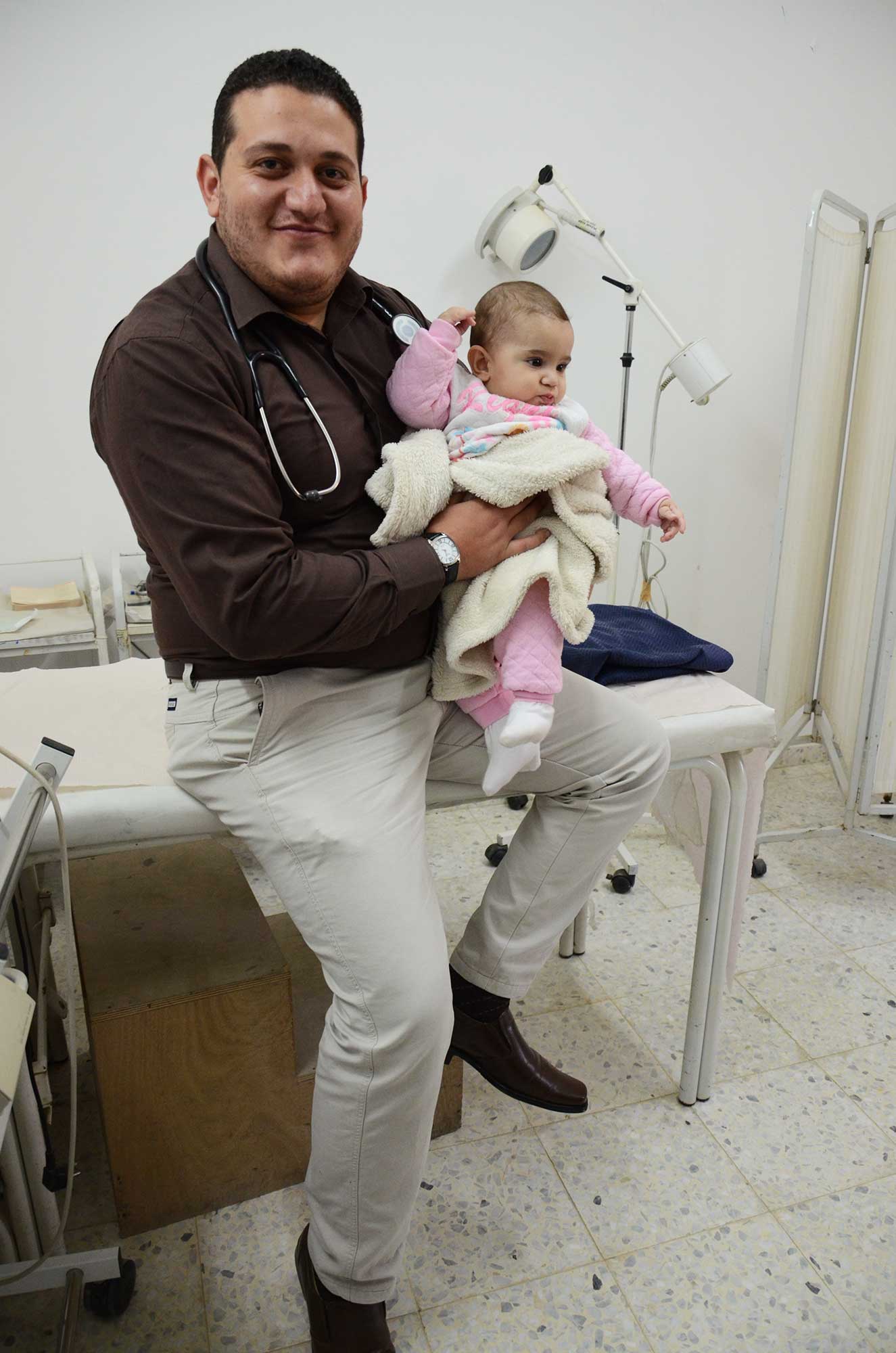 Dr. Jawareesh holds baby Solin during her mother’s routine visit to the clinic. He has been vital in ensuring both the mother and infant’s good health.