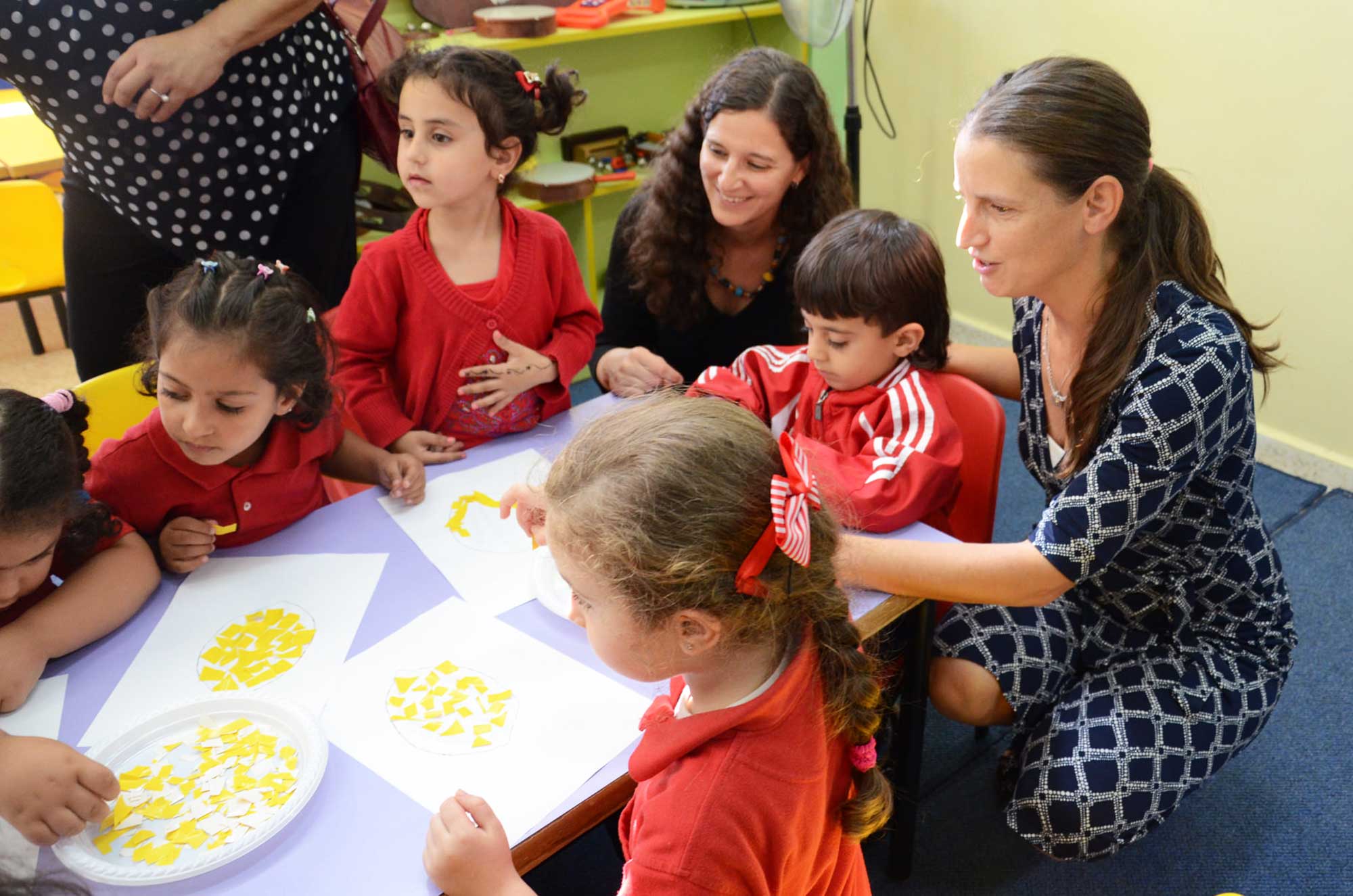 The Gubser sisters help the Al Tireh preschoolers with their arts and crafts project.