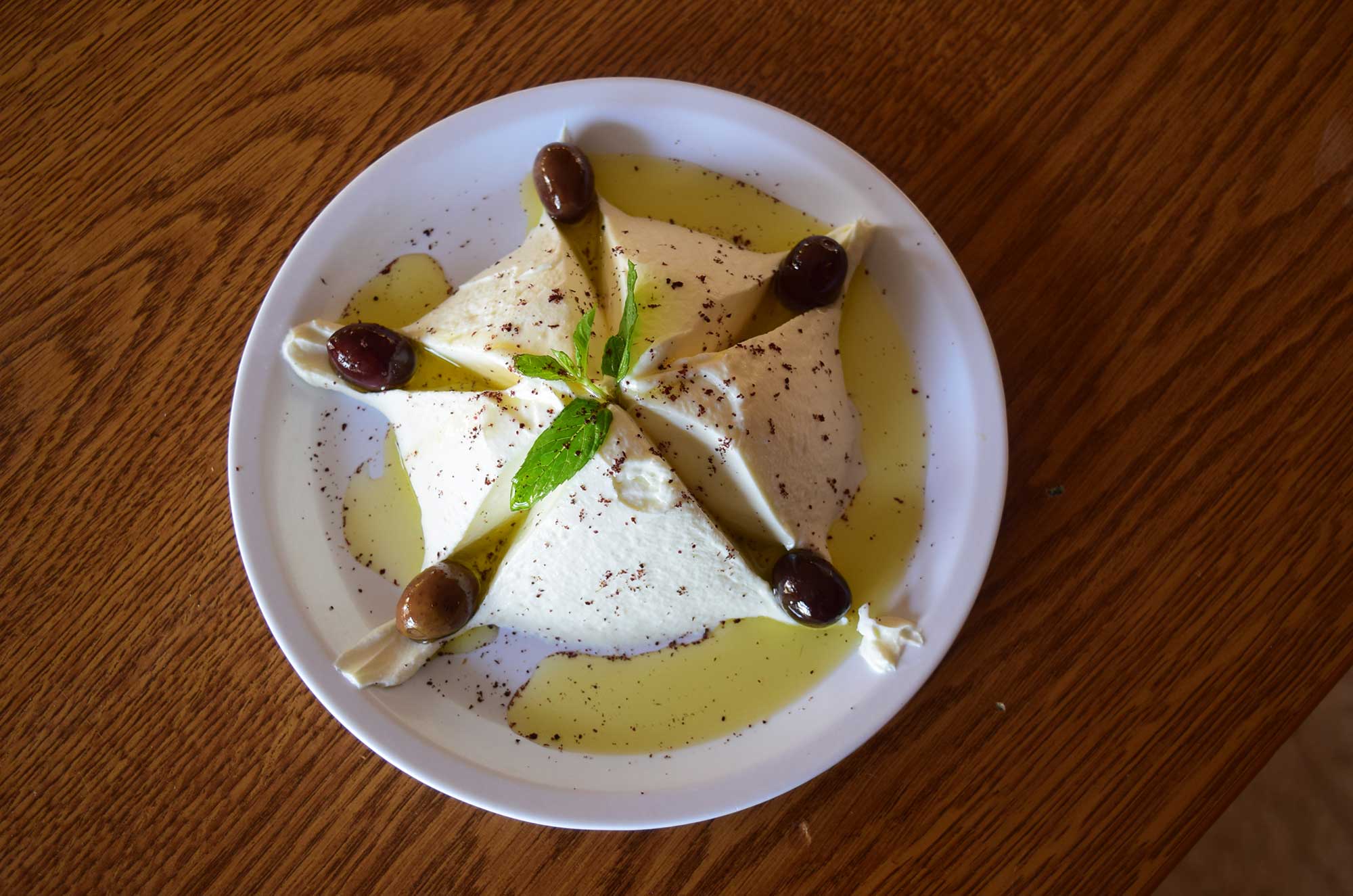 Labneh carefully garnished with olive oil, olives and mint.