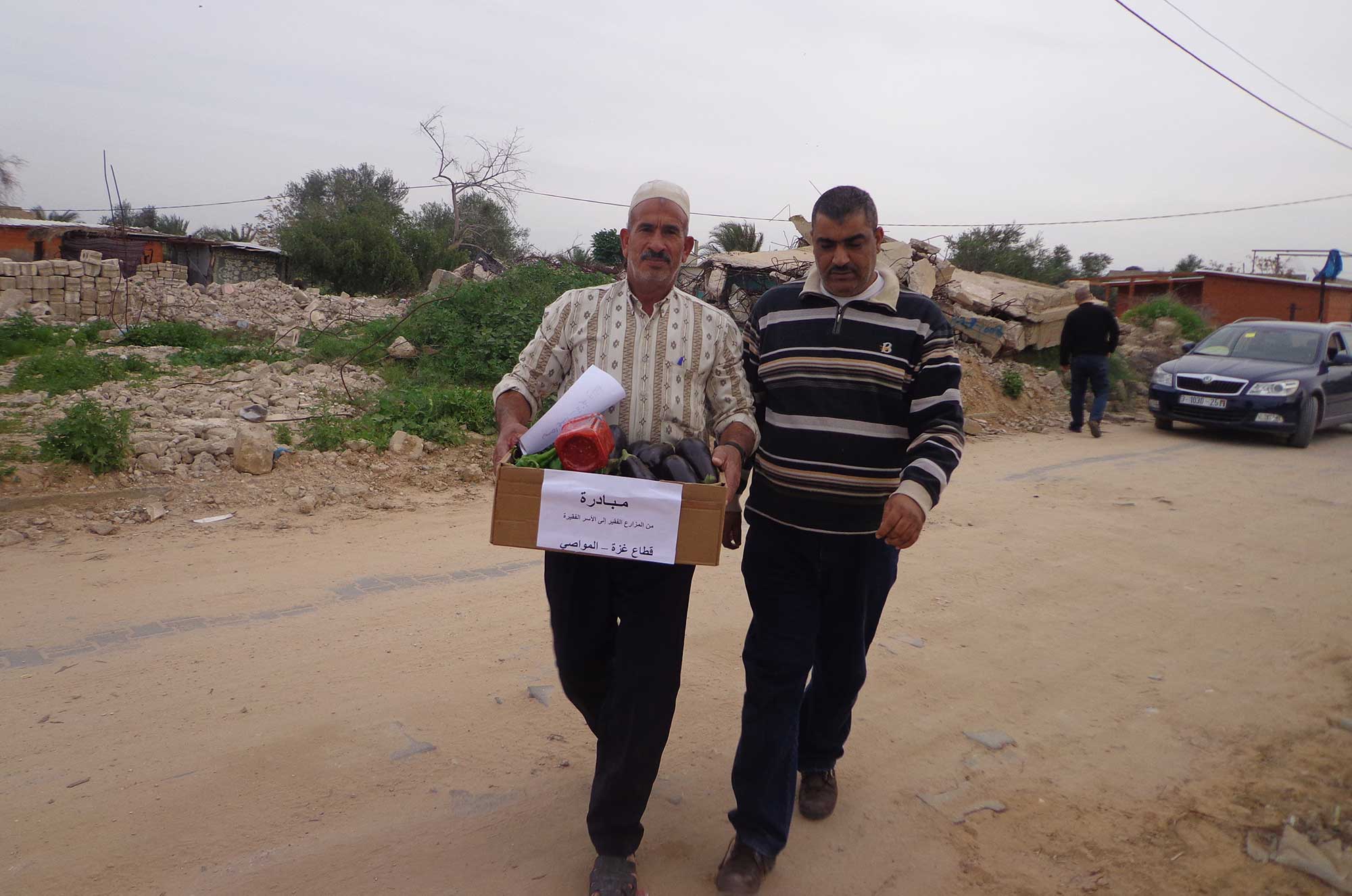 farm3 Gaza farmer Ahmed Zoerob (left) walks down the road to a encampment of prefab shelters carrying a box of fresh produce.
