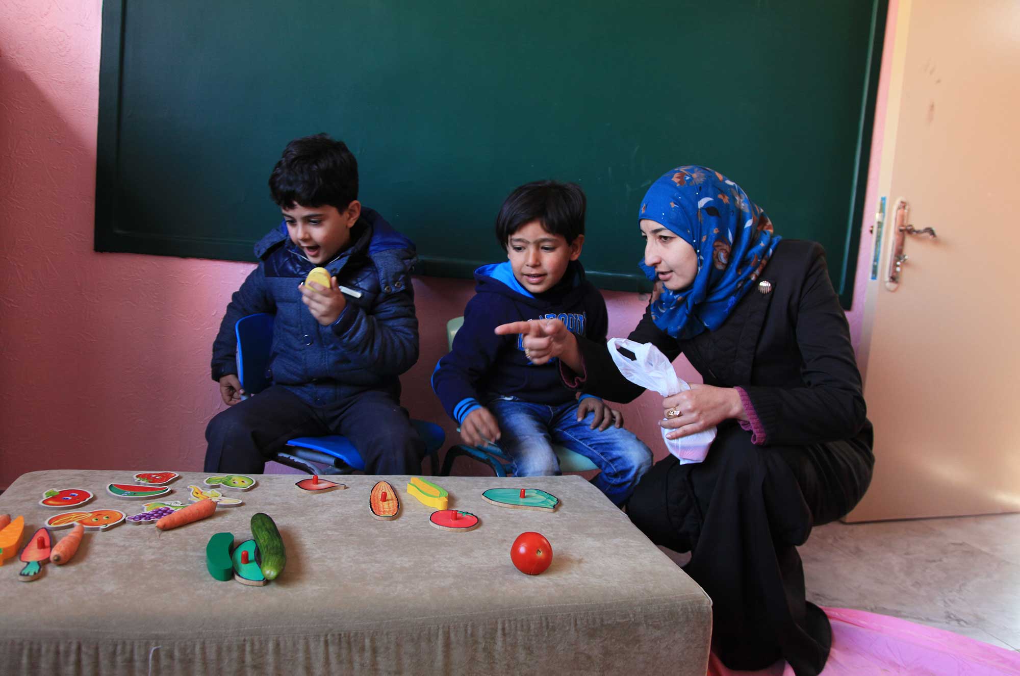 A couple of boys play grocery store with the supervision of teacher Abeer Shawaf.