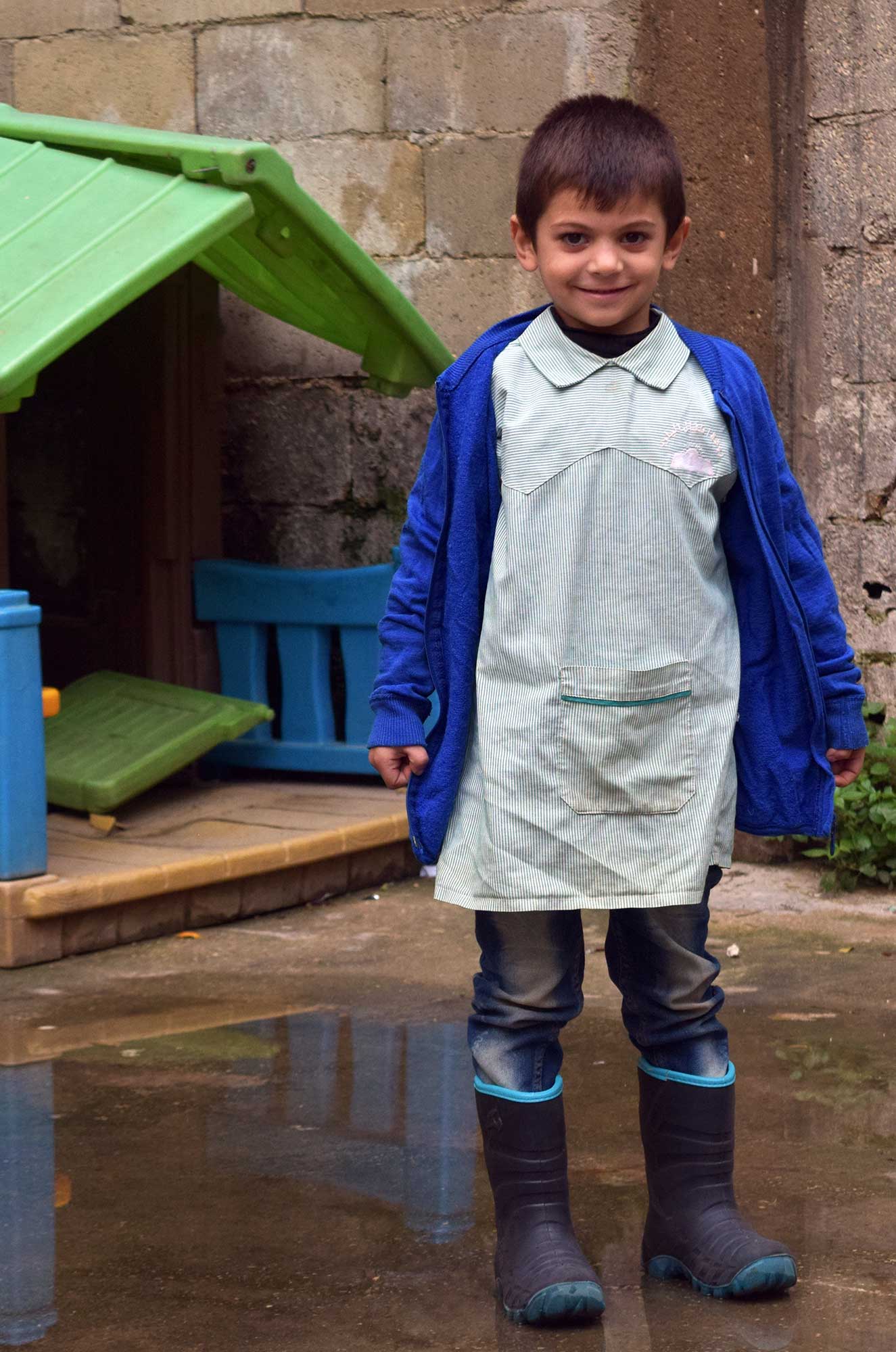 Taha outside the Children and Youth Center in Nahr El Bared, wearing his new boots.