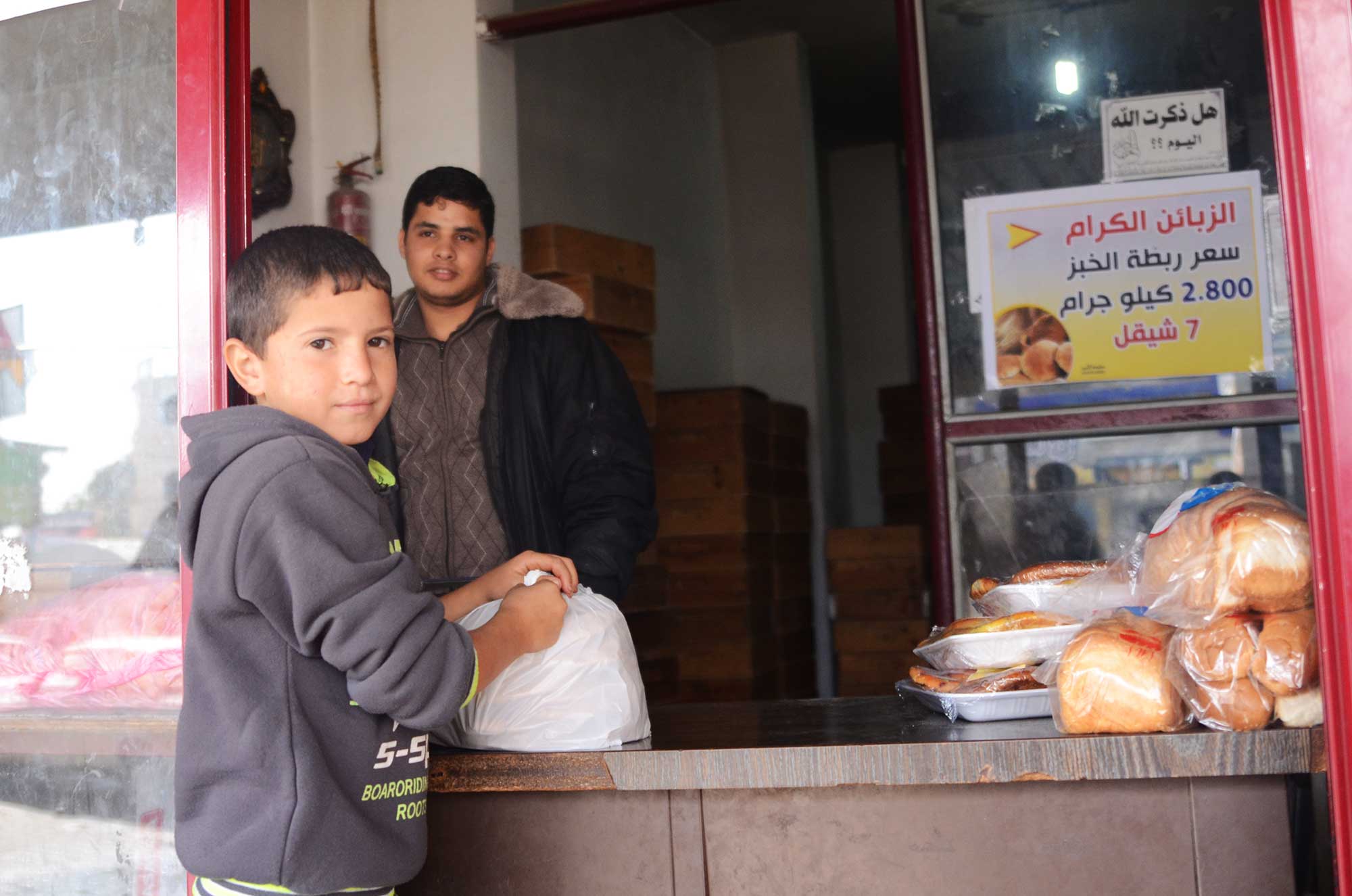 Now that his shop is running smoothly, patrons stop by more often. This young boy is picking up bread from the bakery.