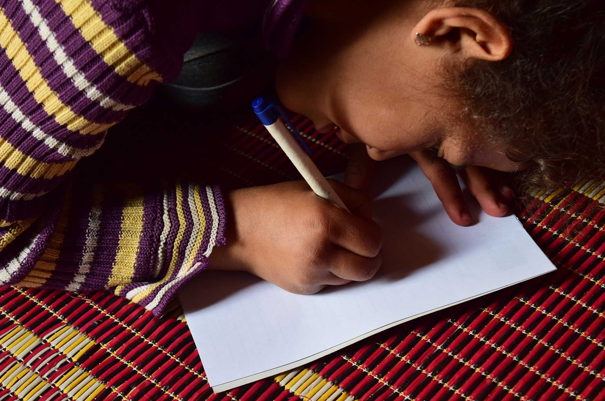 Marwa starts to work on a drawing inside her family’s tent.