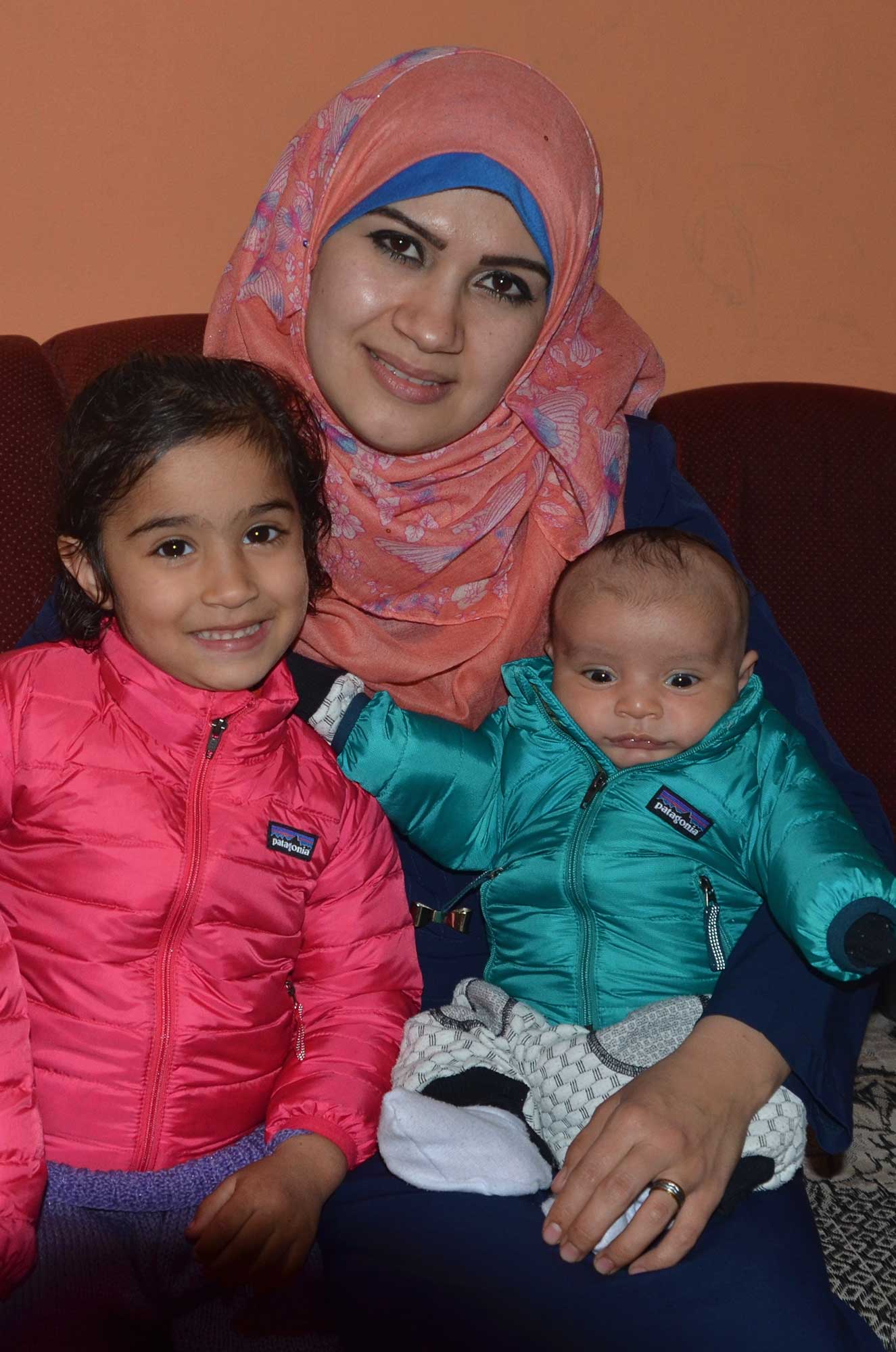 Nurse Siham sits with baby Obaida and his older sister in their new jackets.