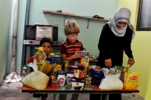 Qamar and her children excitedly look through the items in their food package. Qamar says she'll cook pasta for iftar (the evening meal) and make cheese sandwiches for sohour (an early morning meal).