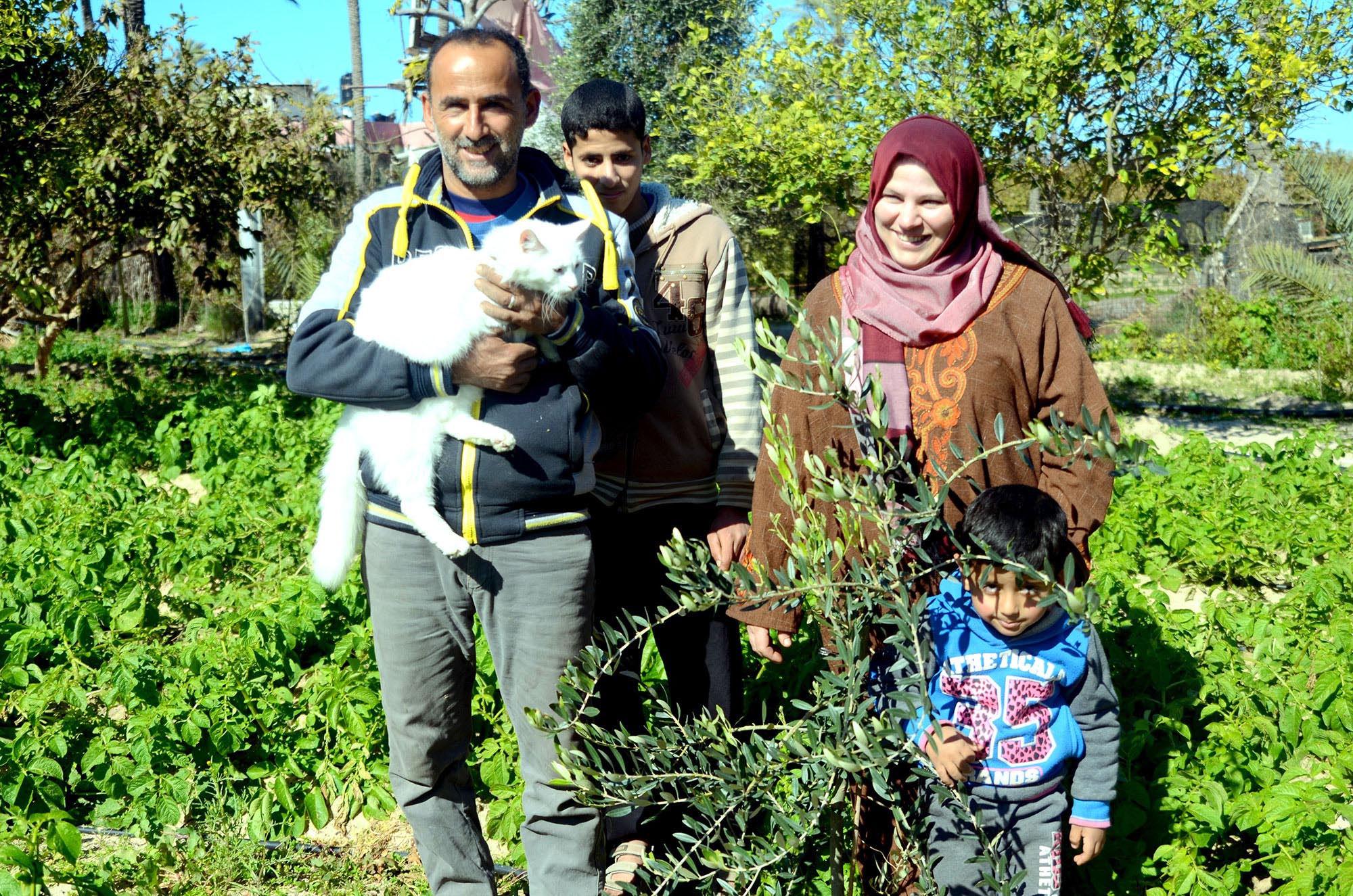 gaza-farmer-with-family-and-cat Gaza farmer, Shaban, stands in his potato field with his family.