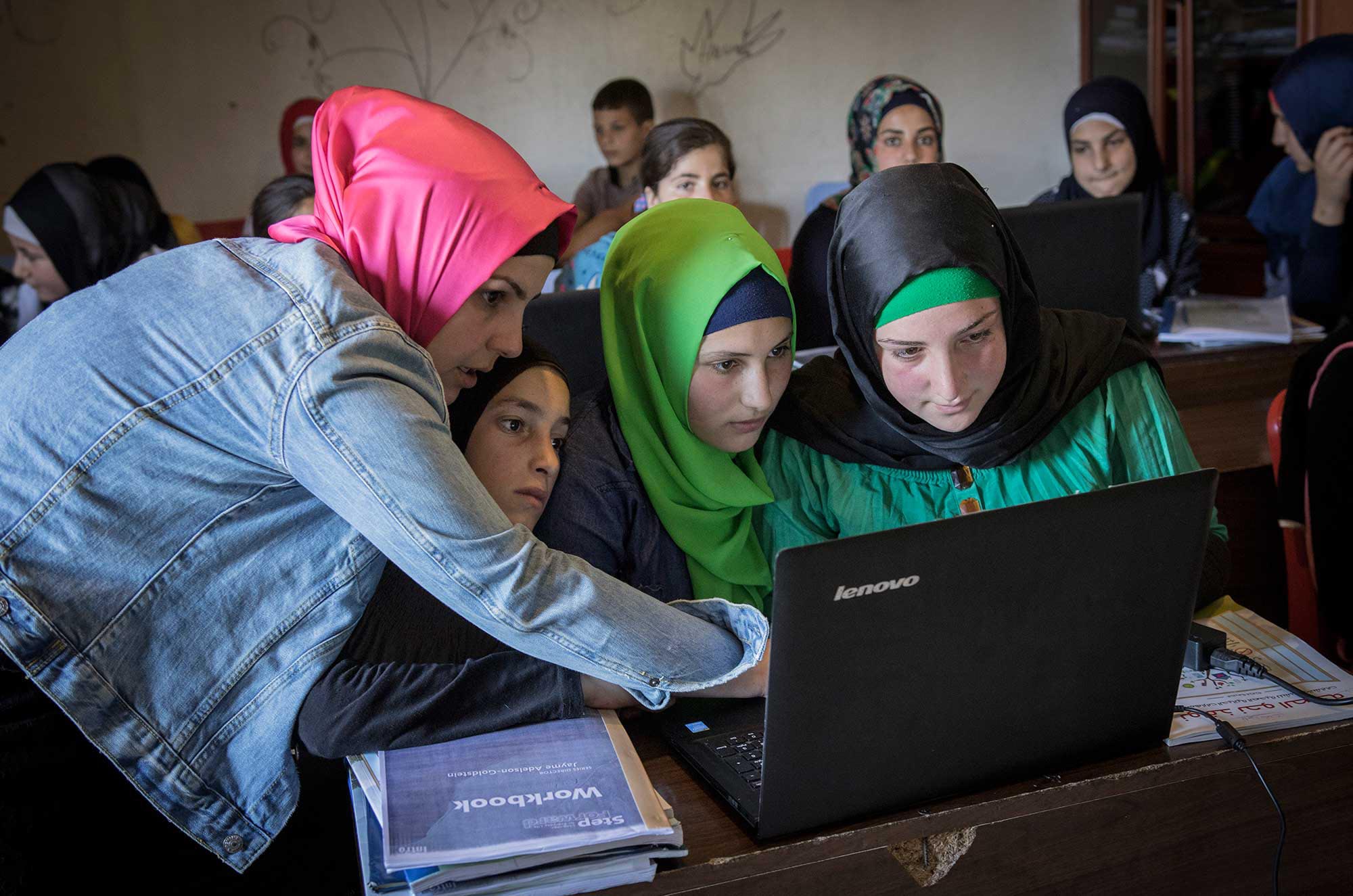Syrian girls learn how to use a computer in Anera's program for refugee education in Lebanon.