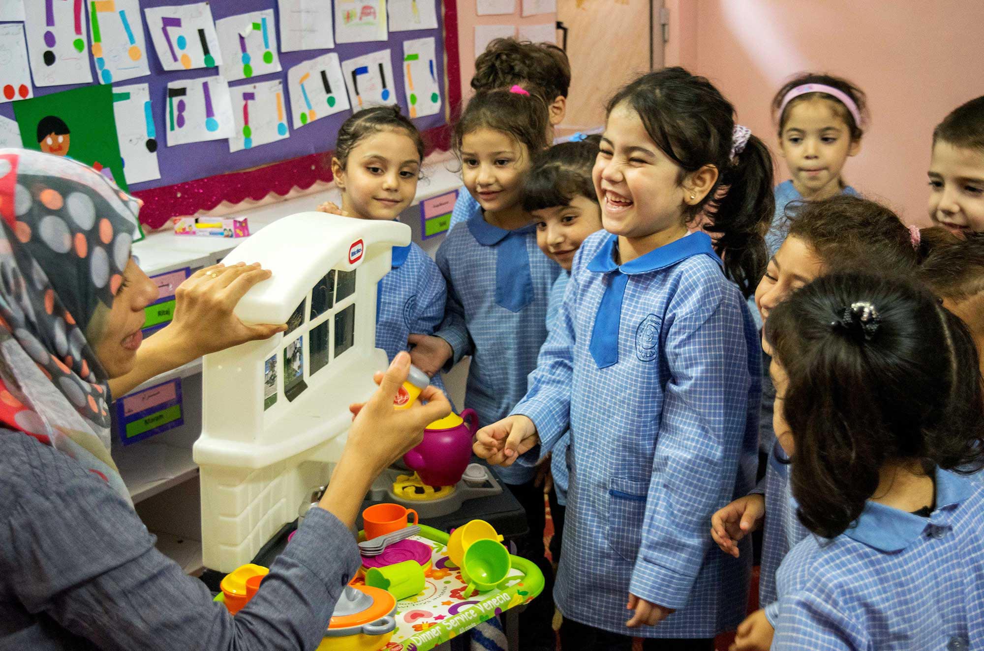 Students at the Anera-renovated preschool in Burj El Barajneh interact with their teacher while playing with the news toys Anera provided.