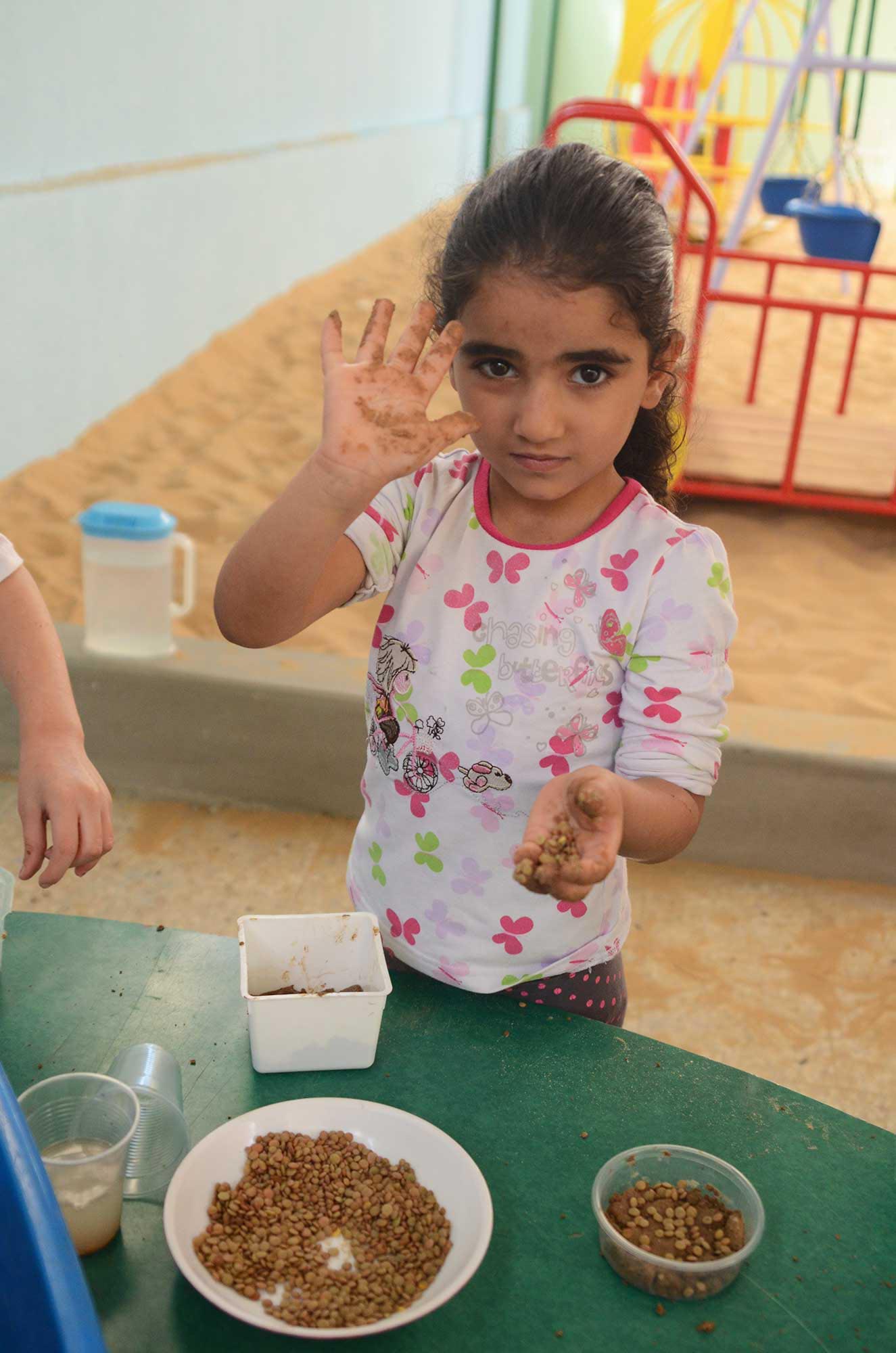 A Gaza preschooler grows seeds as part of an Anera active earning initiative.