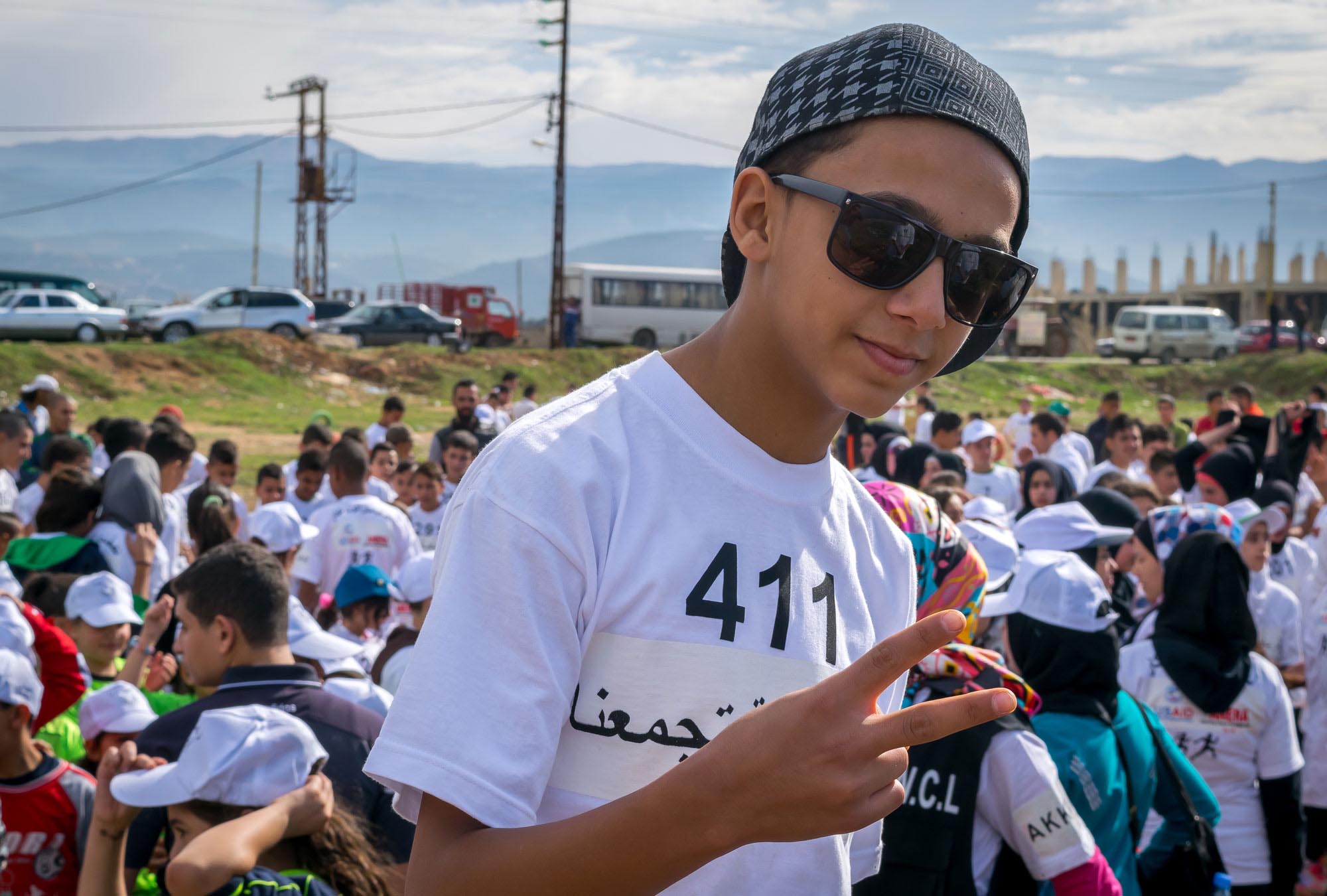 Hossam makes a peace sign to honor ANERA's Sports for Peace program, which brought together 600 youths at the running event in Akkar, Lebanon.
