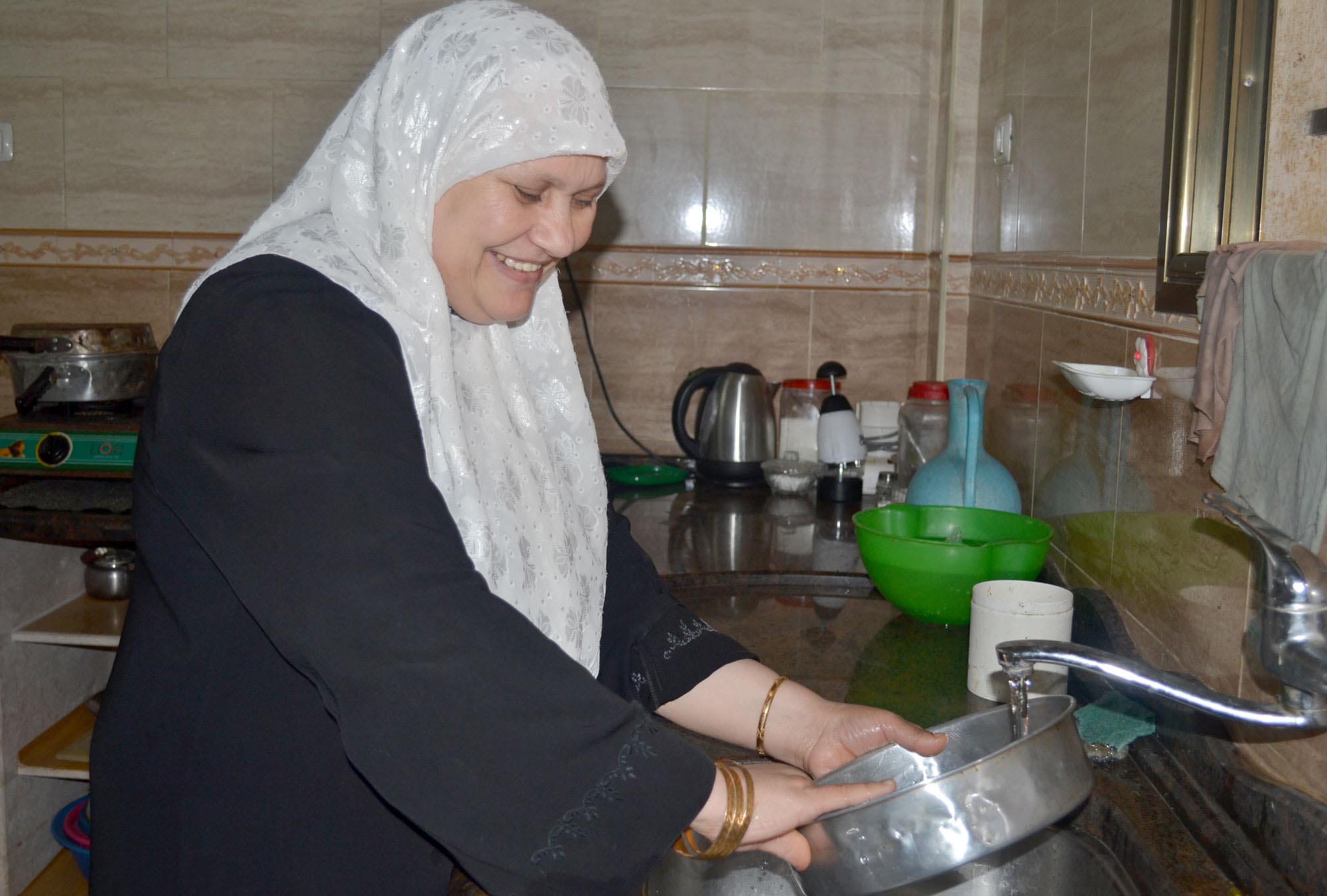 Iftikhaar at her kitchen sink. She says the improved water network Anera installed in her Gaza home makes it easier to cook and clean.