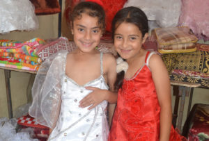 Anera's Gaza Women's Loan Fund beneficiary Fathia lets her two granddaughters model dresses she sells for her youngest clients.