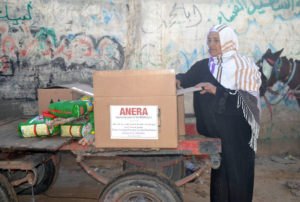 Gaza woman takes home an Anera relief kit of cleaning and hygiene supplies after massive flooding devastated Gaza.