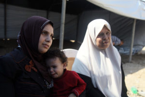 Siham with her baby and mother sitting in their tent in Gaza. They are homeless after the Gaza war.