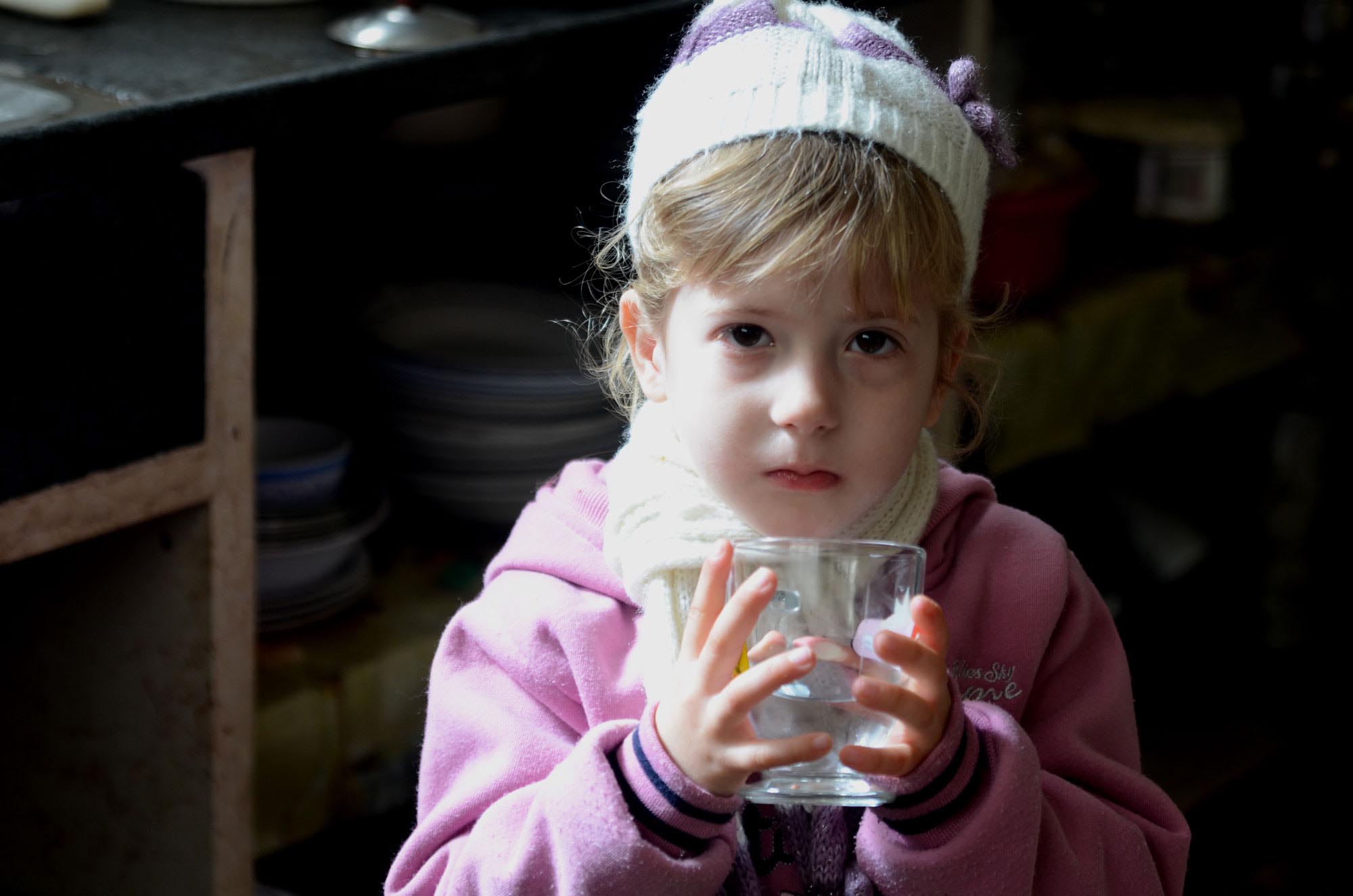 Sabah's granddaughter enjoys a cup of water. She's happy to have clean running water in her home.