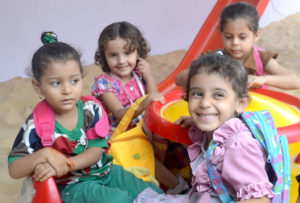 Kids playing on new equipment in the shaded playground that Anera installed at their Gaza preschool.