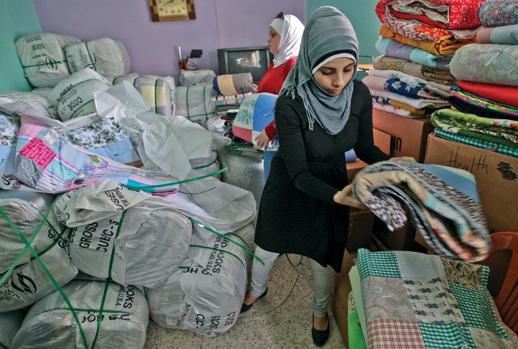 Anera volunteers prepare quilts for distribution to refugee families at the El Bass camp in Lebanon.