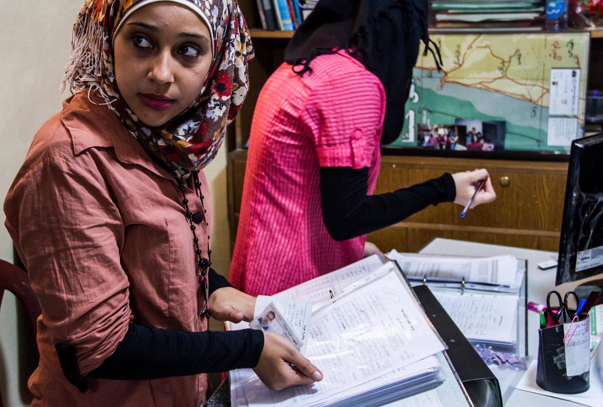 Relief-Palestinian-Women-Refugees-from-Syria-1 Anera volunteers go through names of recipients in Shatila camp before giving families relief kits.