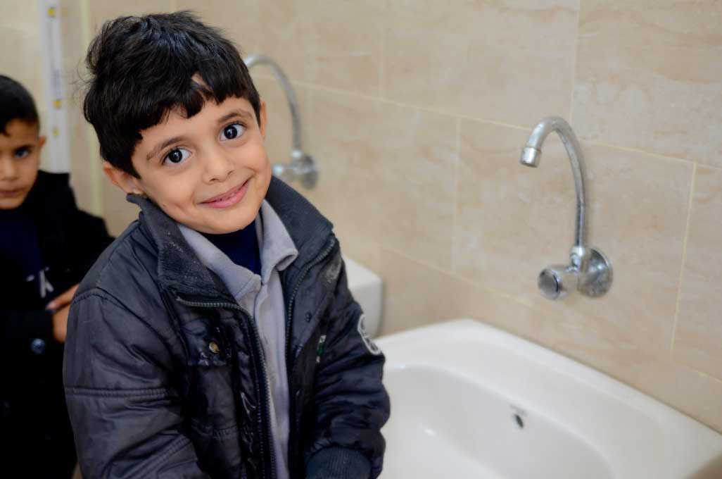 A child washes his hands using a new sink with clean running water at El Hekayet Preschool.