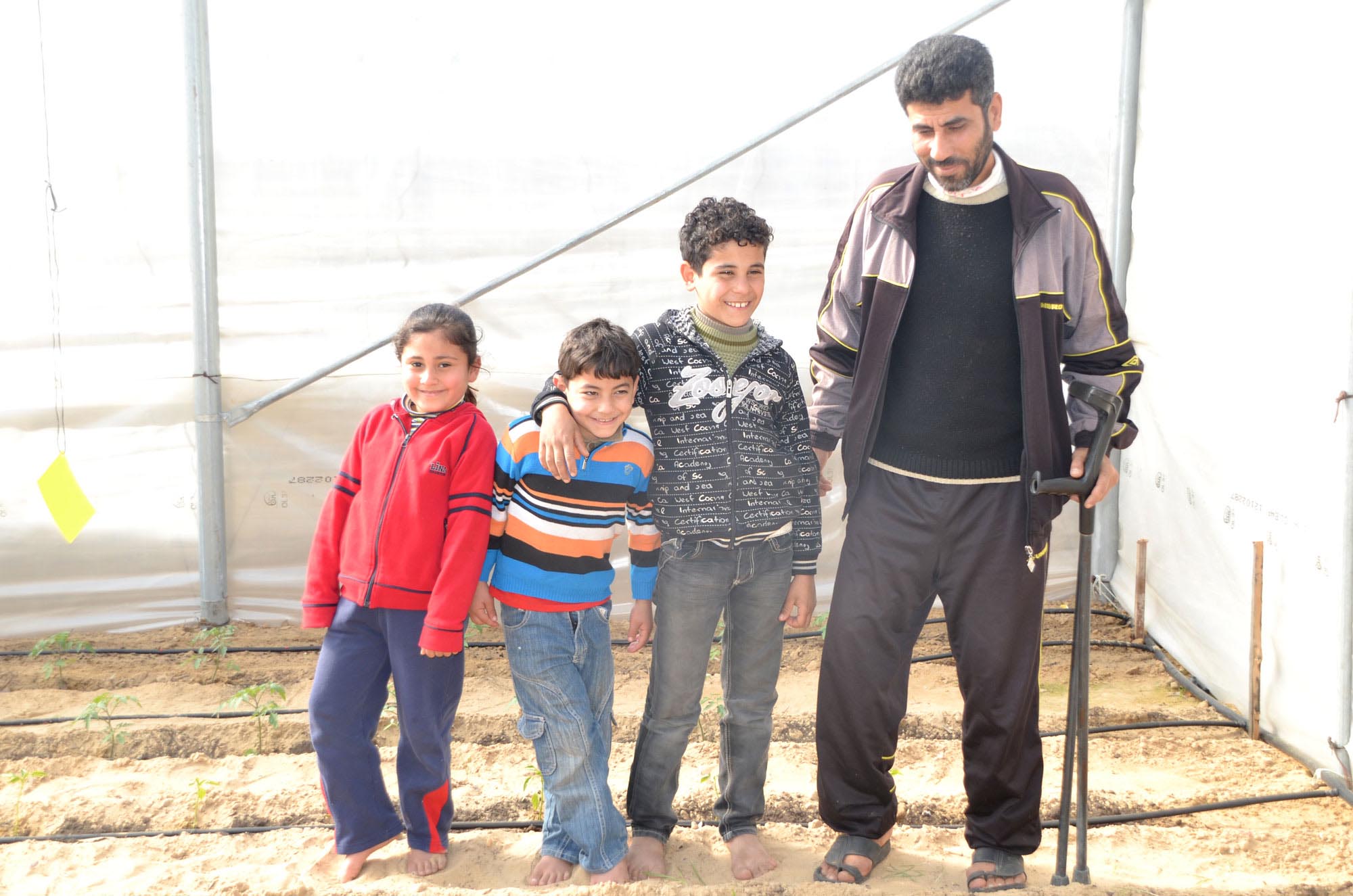 Bassem and his family inside the greenhouse Anera installed in their Gaza yard.