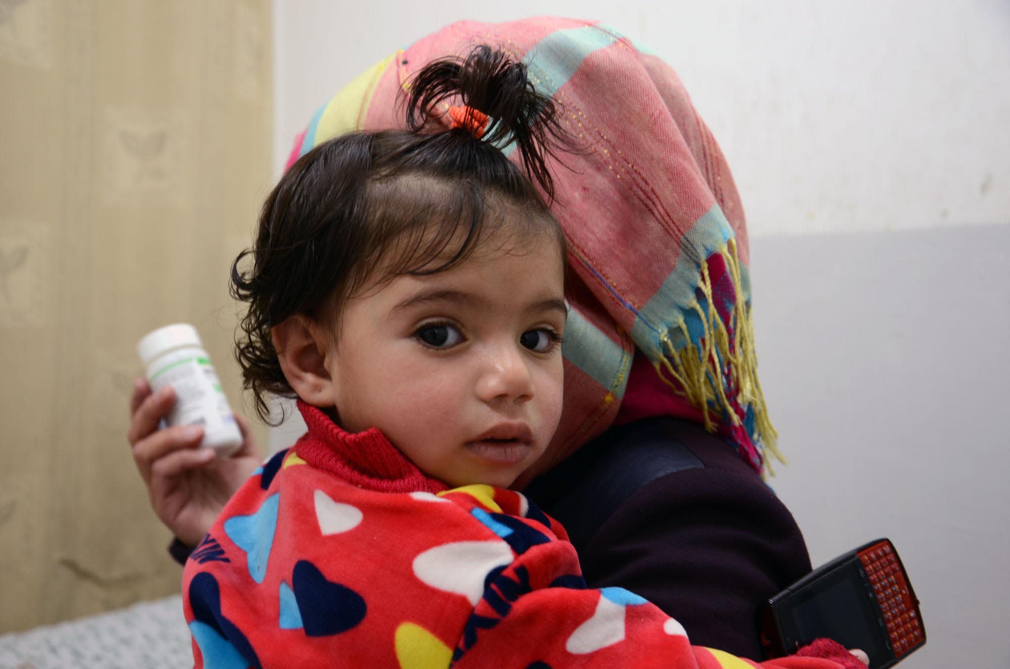 For Families in Idhna, a Charitable Clinic Makes All the Difference Celia is grumpy now, but soon she'll be feeling better than to antibiotics delivered by Anera and donated by AmeriCares.