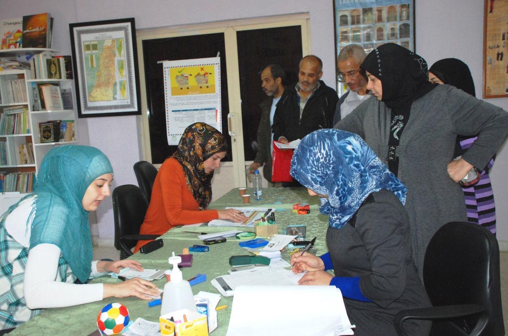 Volunteers in Burj Al Shemali camp hand aid vouchers to Palestinian refugees from Syria who sought shelter in Lebanon.