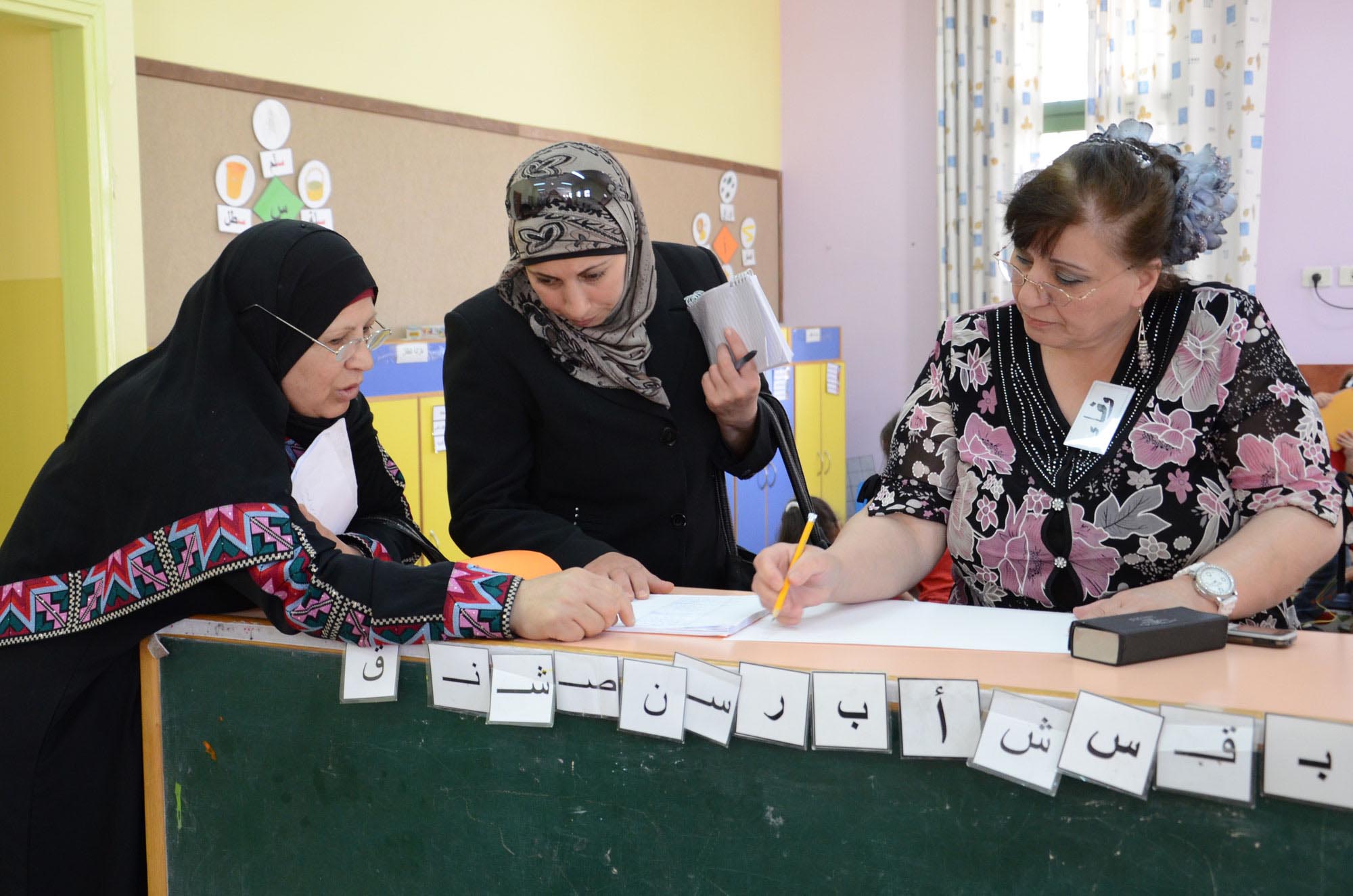 Three early childhood development teacher trainees check their notes after an Anera in-service training class in the West Bank.