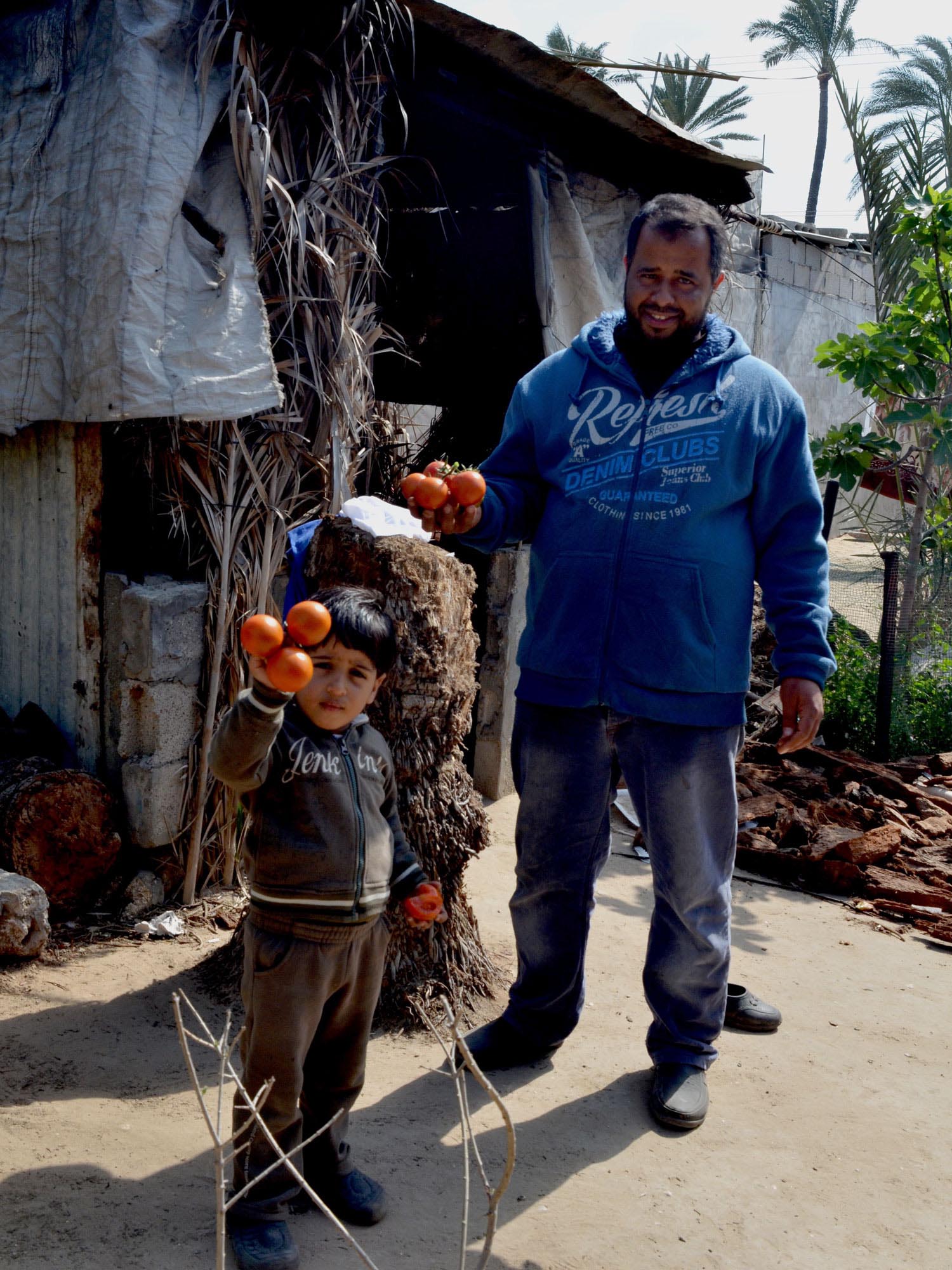 Khaled and one of his children in front of their home in Deir El Balah, Gaza.