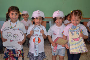 Anera summer campers in Gaza show off their colorful cutouts of toothbrushes, toothpaste and combs as part of a game about healthy habits.